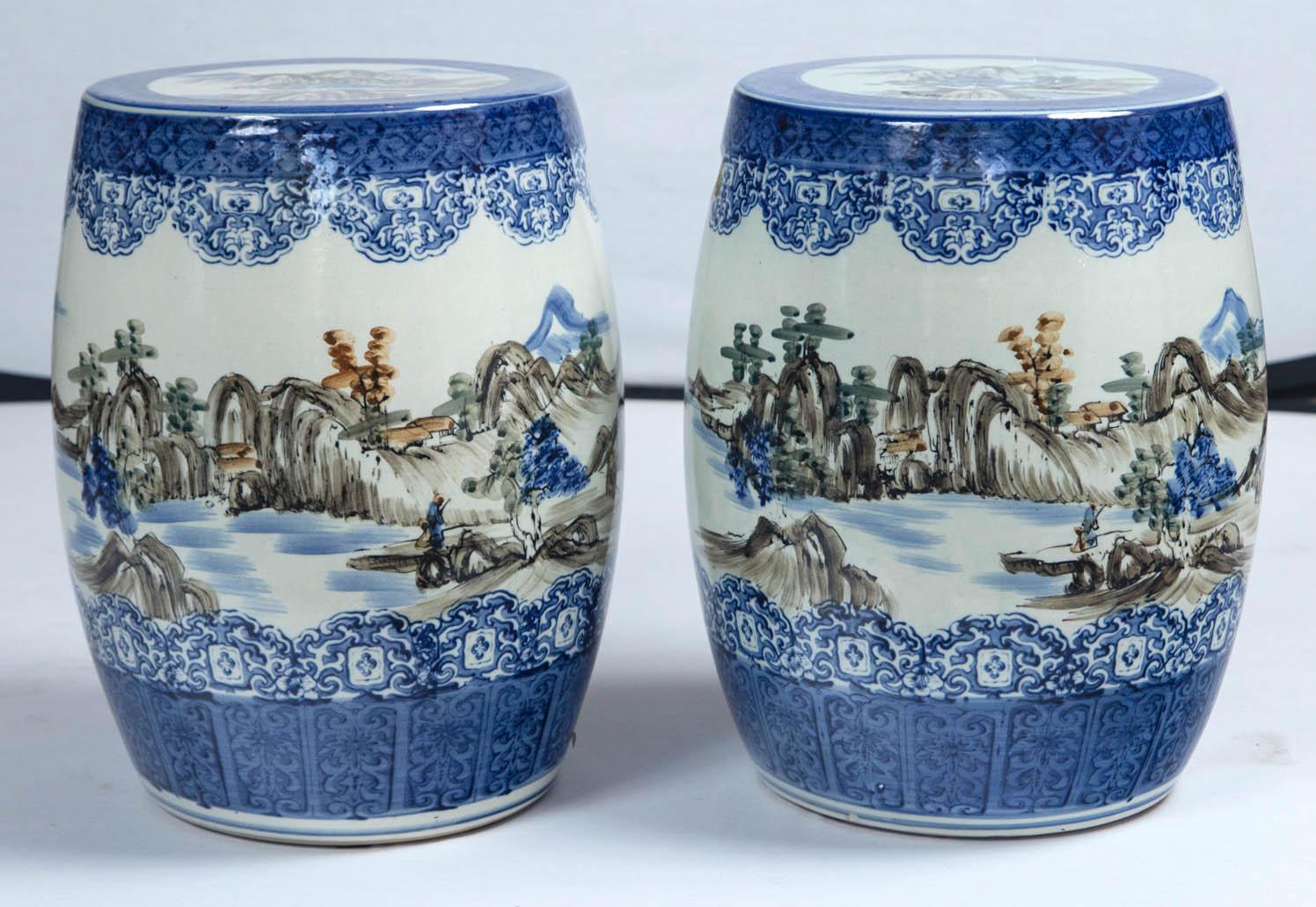 Pair of Japanese ceramic garden stools, early 20th century. Cobalt blue glaze design border at top and bottom. Overall rural landscape with mountains and lake. Design reminiscent of Japanese watercolor paintings.
