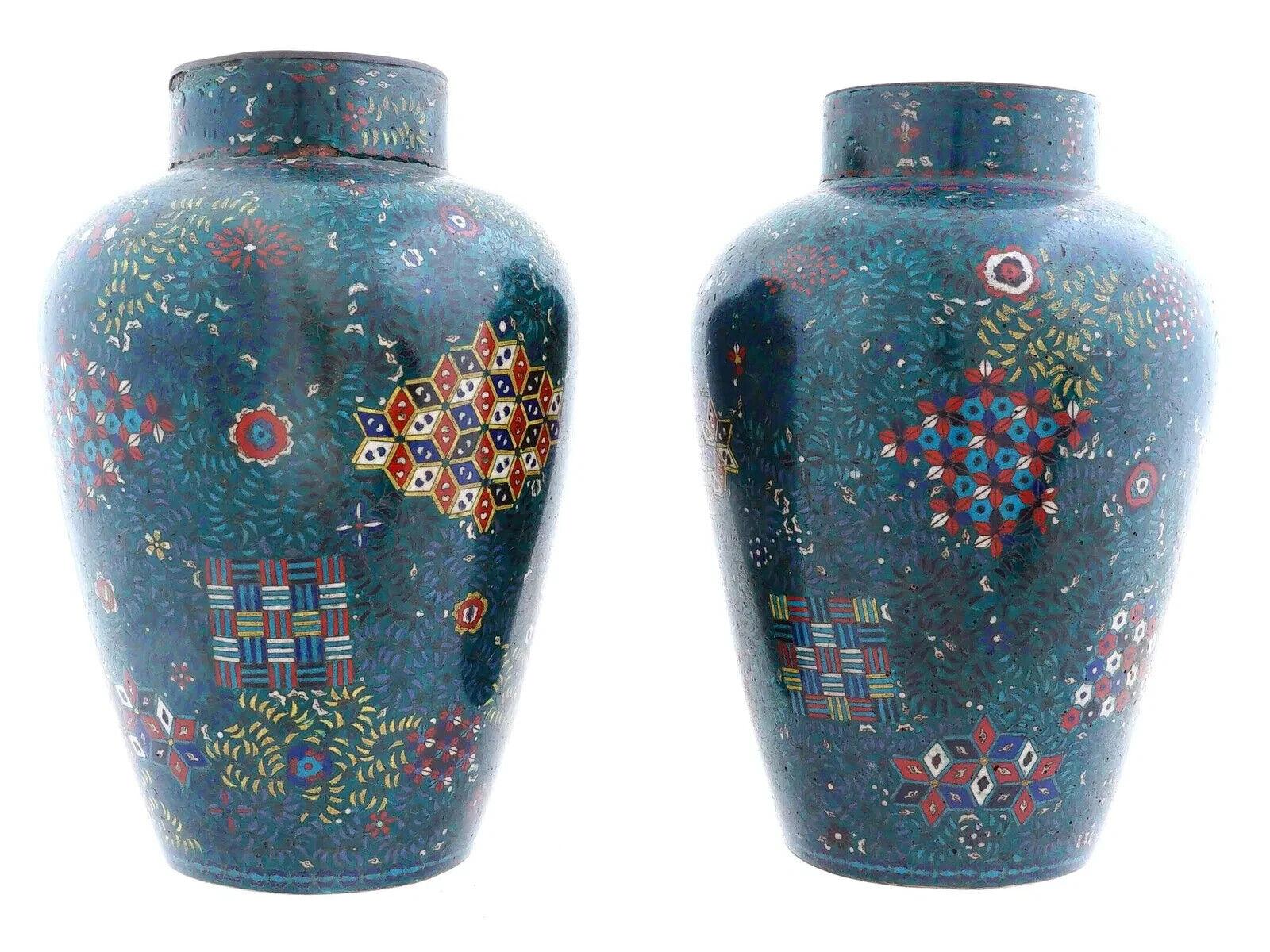 Ein Paar symmetrische japanische Vasen aus Emaille und vergoldetem Kupfer. Die Außenseiten der Waren sind mit polychromen, in Cloisonne-Technik gefertigten Blumen-, Laub-, Blattschnecken- und geometrischen Ornamenten verziert. Der Hals und der
