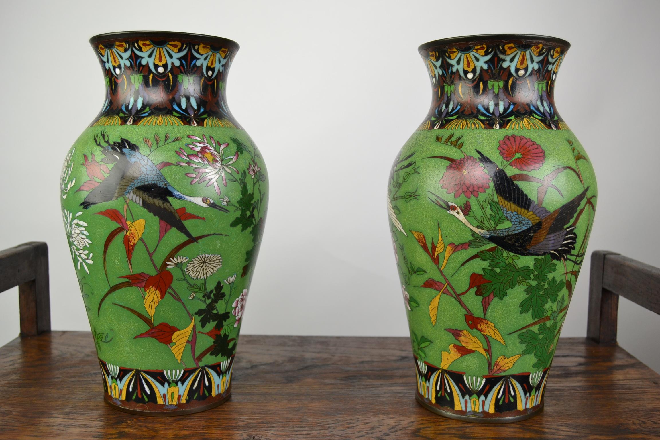 Pair of Art Deco Japanese Enamel on Copper Vases circa 1920 -1930. 
Lime Green Vases with Manchurian Cranes and different flowers , 
like Peonies, Chysanthemums, Irises and other flowering plants. 
Blue Interior and base. 
The Borders around the