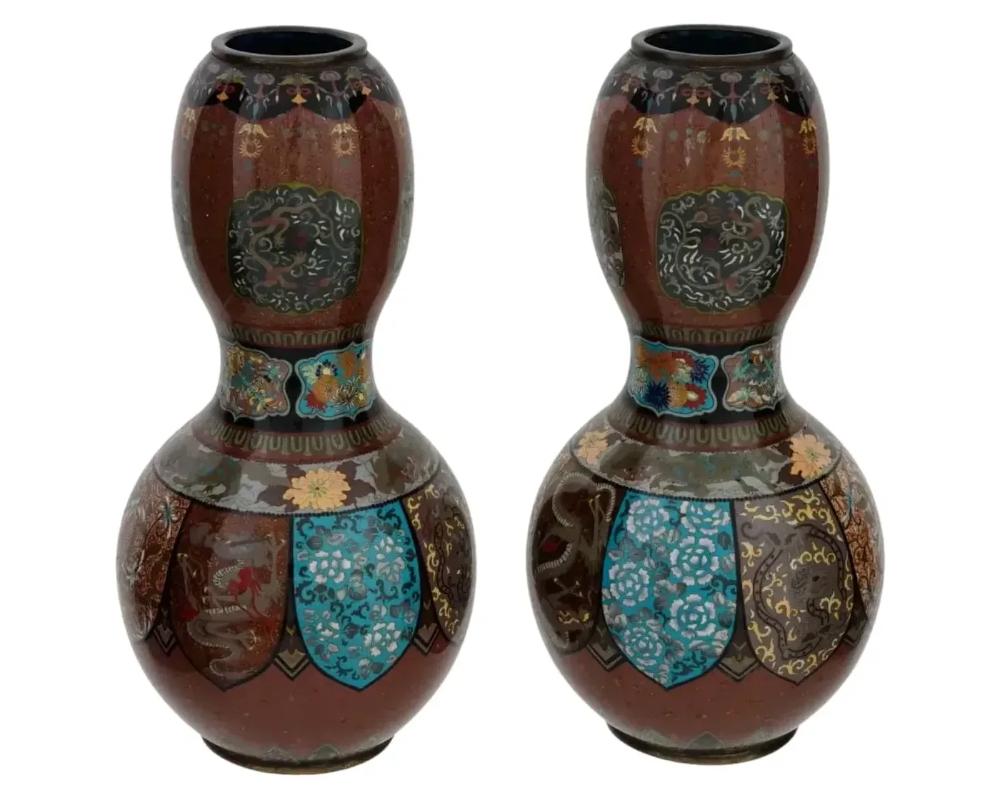 A pair of rare large Japanese, late Meiji era, double gourd enamel vases. Each ware is enameled with polychrome bands and panels with dragon, floral, foliage, and foliate scroll ornaments made in the Cloisonne technique. The neck and the base are