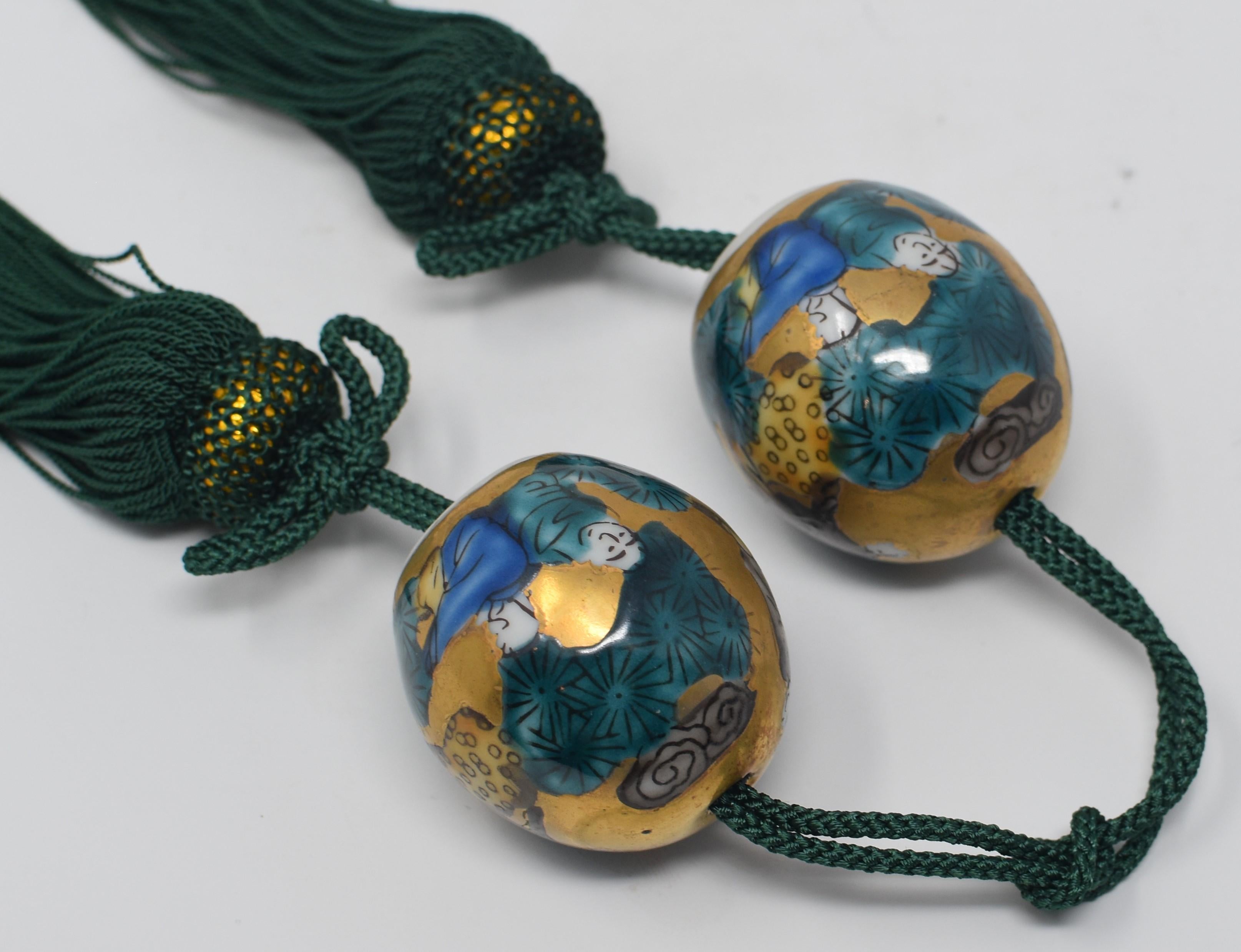 Unique Japanese gilded contemporary pair of porcelain scroll weights (fuchin), extremely intricately hand painted in Mokube pattern, one of Kutani's most recognized and beloved patterns, in green and blue on a beautiful egg shaped body in gold. Each