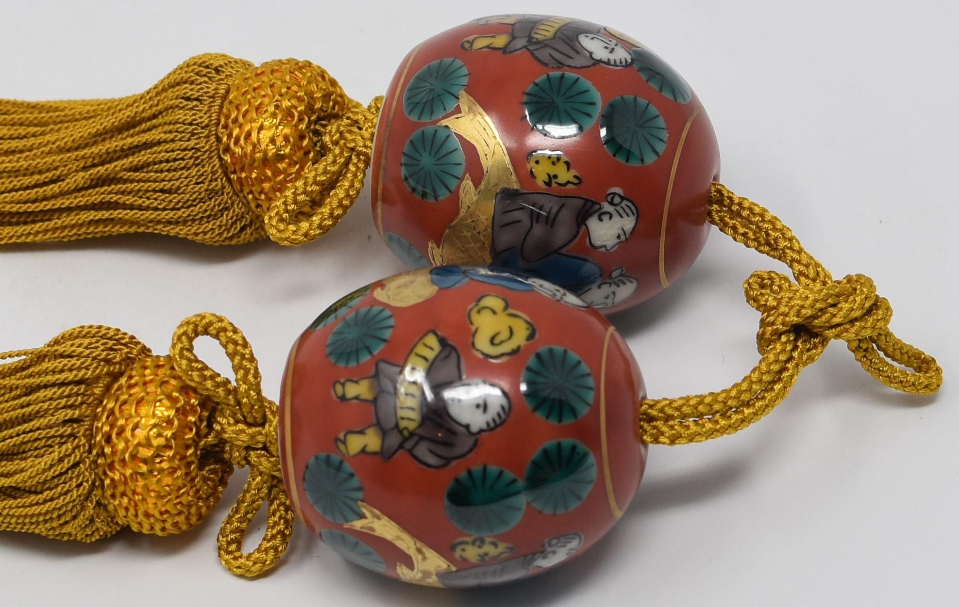 Attractive Japanese Kutani gilded contemporary pair of porcelain scroll weights (fuchin), extremely intricately hand painted in Mokube pattern, one of Kutani's most recognized and beloved patterns, in mokubei's signature red and green on a beautiful