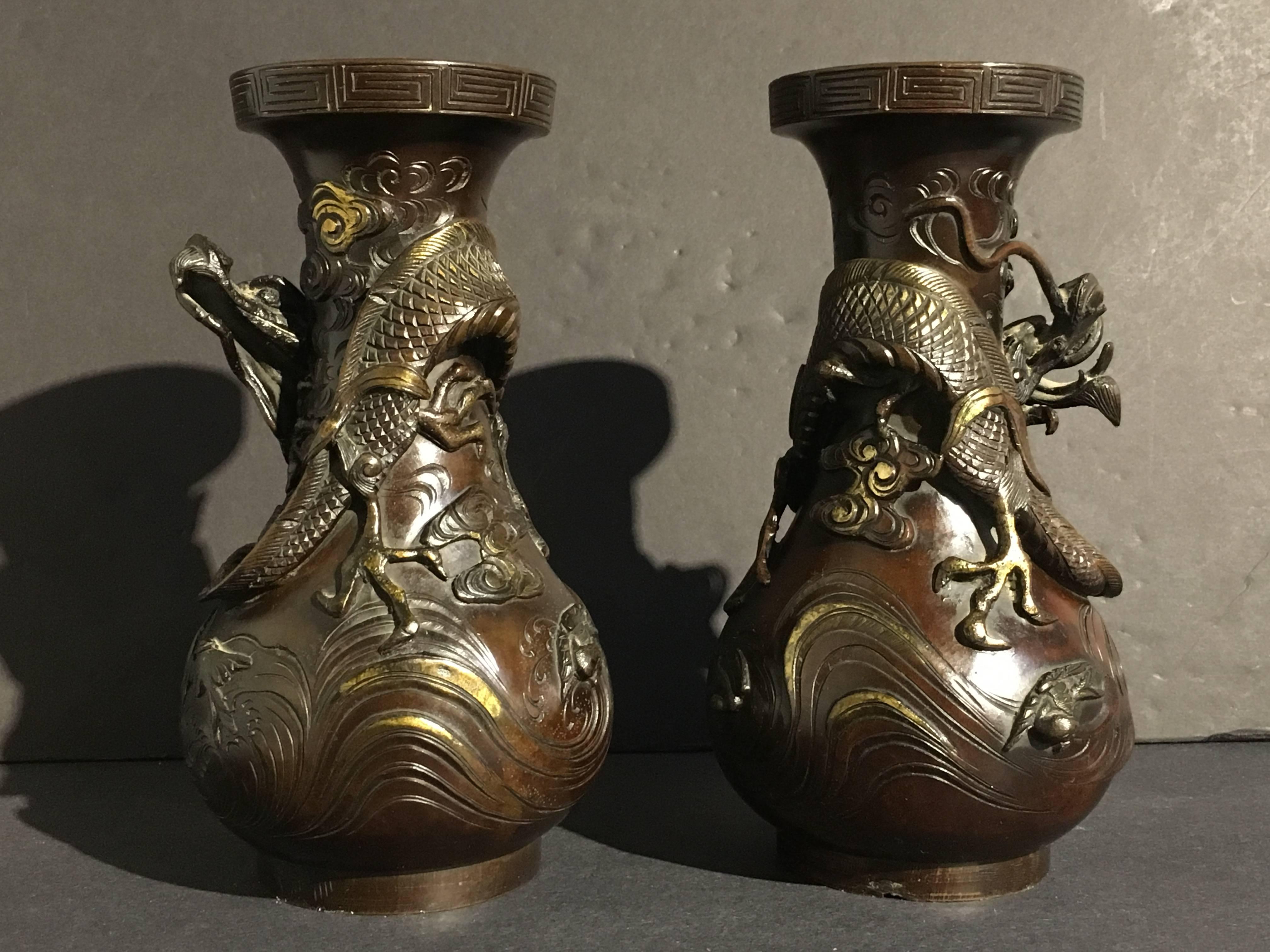 Ein Paar gut gegossene und dramatische japanische Drachenvasen aus vergoldeter Bronze, Edo-Periode, frühes 19. Jahrhundert. Die schweren, birnenförmigen Bronzevasen zeigen jeweils einen einzelnen, sich windenden Drachen in Hochrelief, der in den