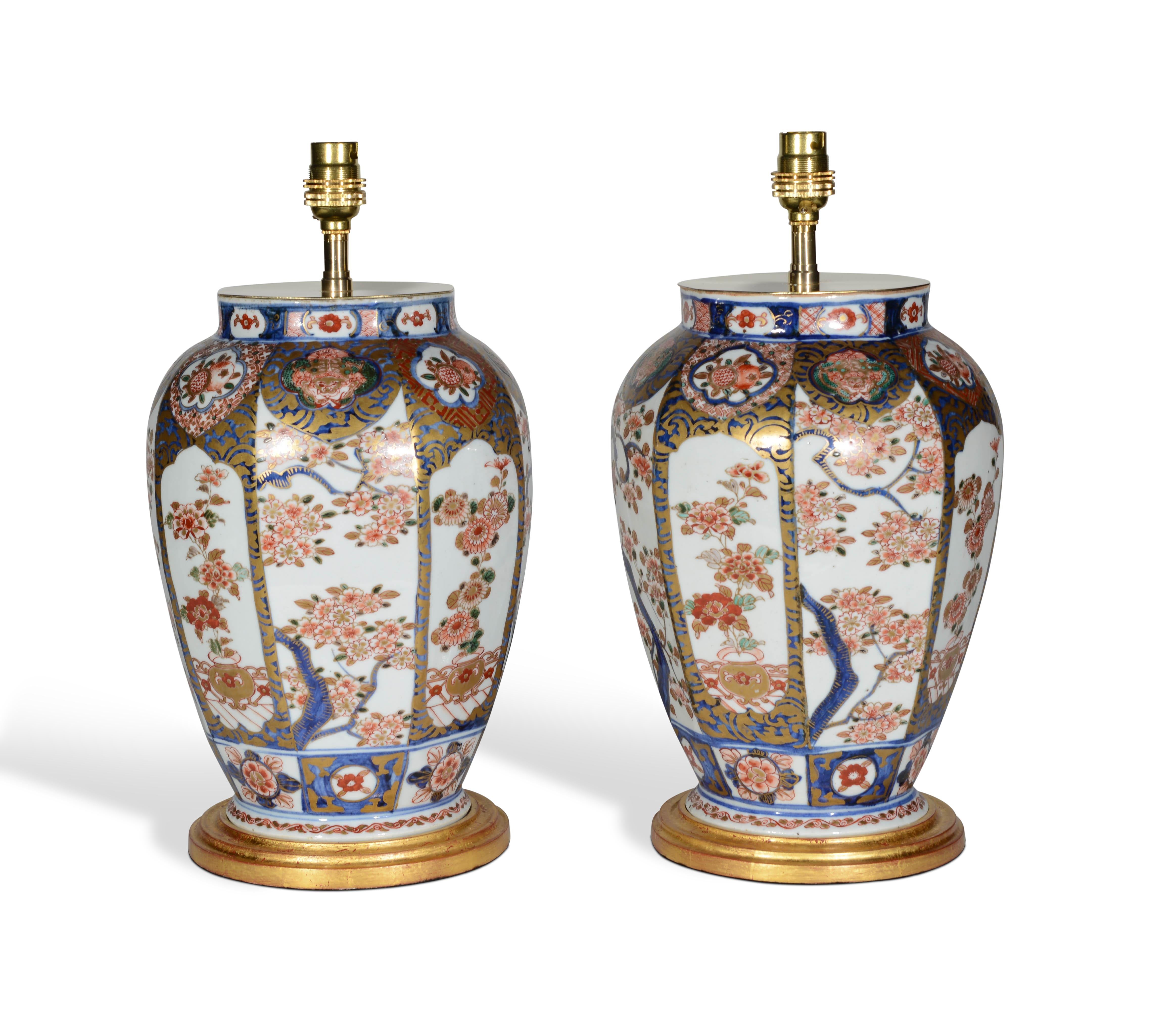 A fine pair of small mid 19th century Japanese vases, decorated throughout in the typical Imari palette of iron red and blues on a predominantly white background with gilded highlights throughout, each panel particularly finely painted with