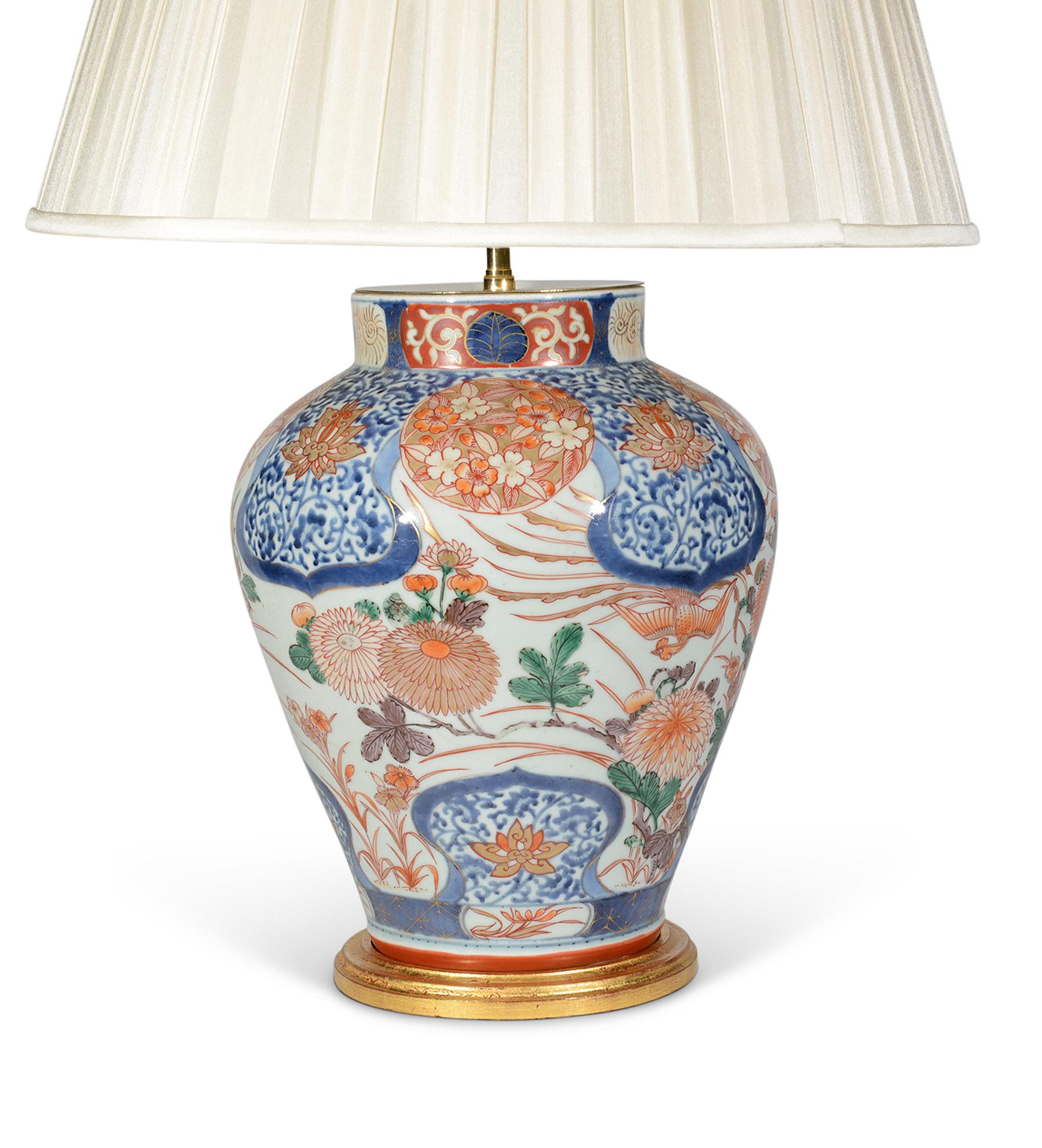 A very fine and rare pair of early 18th century Japanese Imari baluster vases, decorated in the typical Imari palette of tones of blues and iron reds with gilded highlights on a predominantly white background, the main panels with superb flowering
