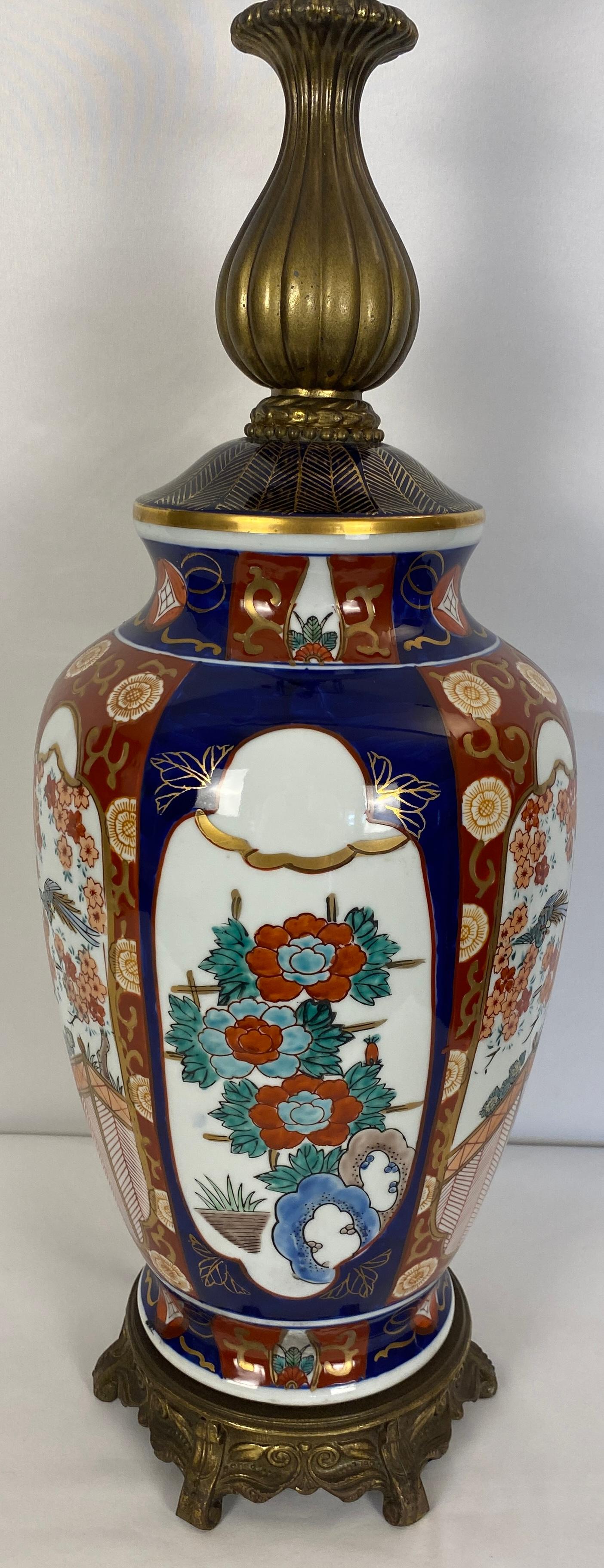 Zwei Lampen im Stil des japanischen Imari-Porzellans, dekoriert mit traditionellen Figuren, Blumen und Pagoden in Rosa- und Grüntönen auf weißem Grund in dekorierten Bordüren, 

Sie wurden von der Firma Honi Chilo in der Mitte des Jahrhunderts