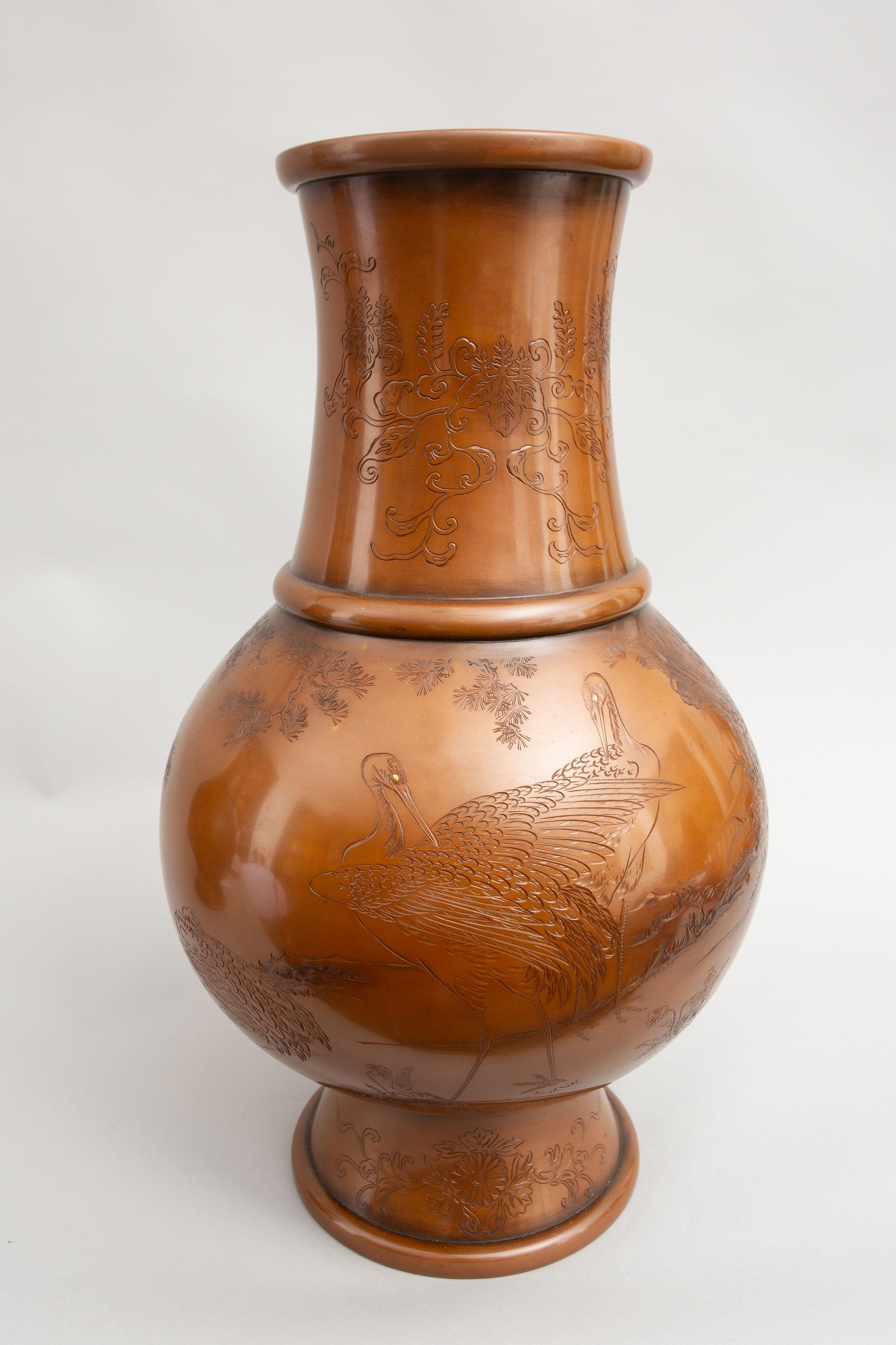 Early Meiji period (1868-1912) bronze vases, incised, detailed designs on each vase. One vase is decorated with a family of cranes at a rocky water's edge, with flowers and an old pine tree. The other vase depicts turtles at a rocky water's edge