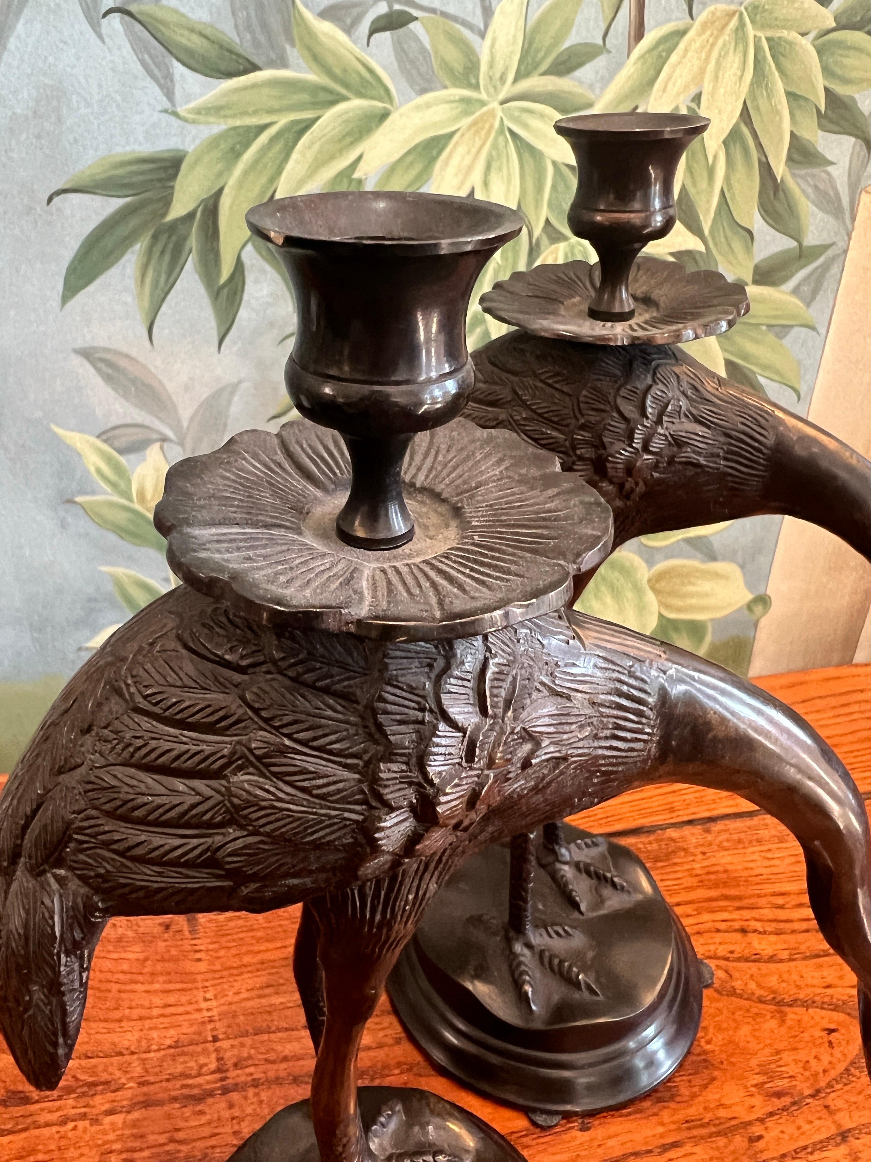 Ein Paar japanische Bronzekerzenhalter in Form von Kranichen aus dem späten 19. und frühen 20.  Diese stammen aus der Meiji-Ära (1868-1912).

Jeder Kranich steht anmutig auf einem Sockel, die Hälse sind anmutig geschwungen und nach unten gerichtet. 