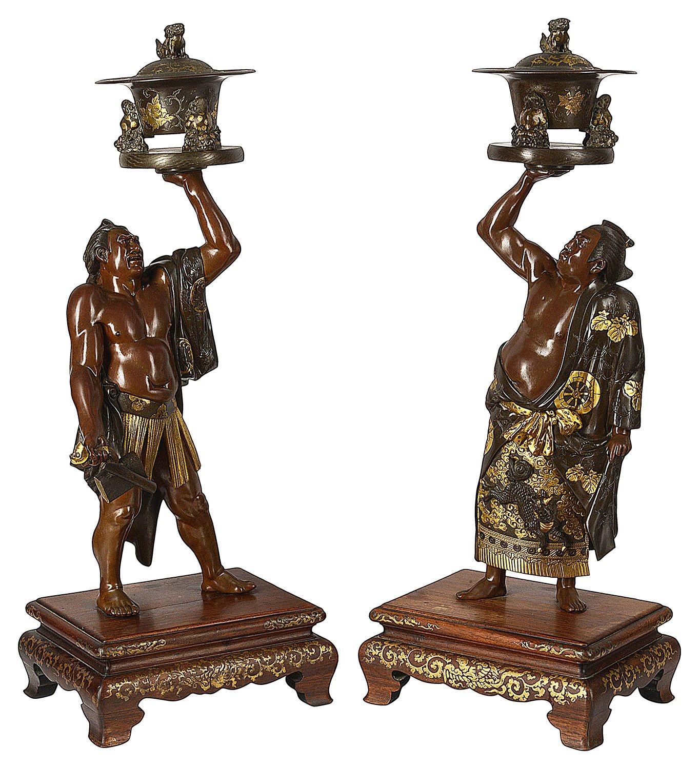 A wonderful, fine quality pair of Japanese Meiji period (1868-1912) Miyao tsukuru signed figures of two Sumo wrestlers, each bare chested with kimonos thrown over their shoulders, holding aloft cyclindrical covered censers, one wrestler wearing a