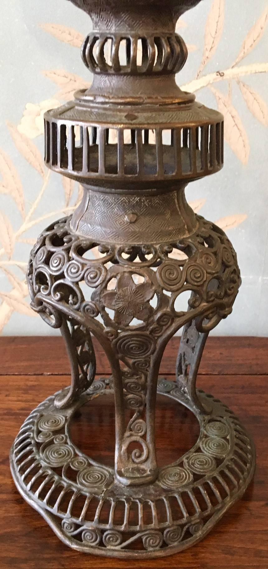 A pair of 19th century antique Japanese ornately decorated openwork metal candle stands.