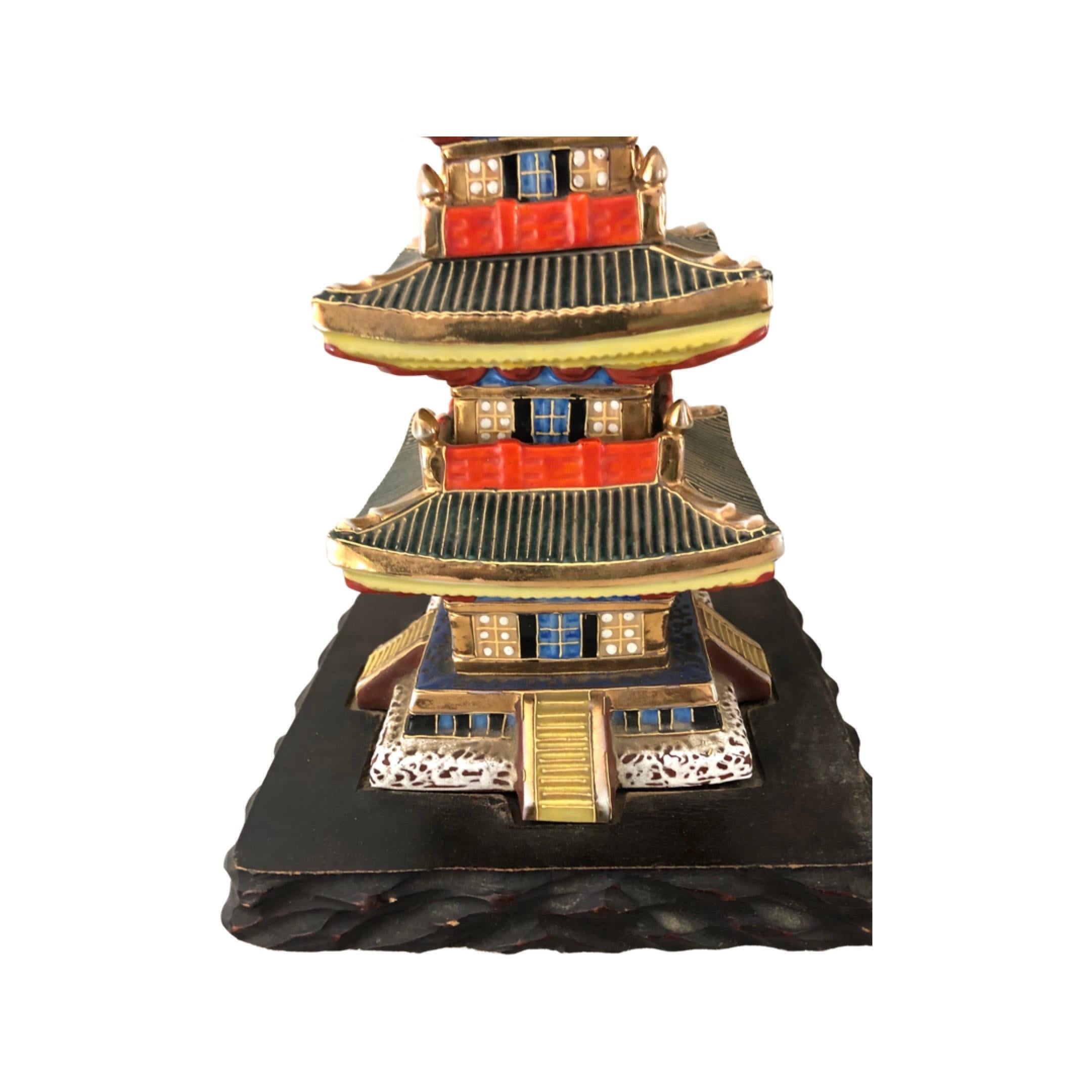Rare paire de lampes japonaises en porcelaine en forme de pagode. Magnifiquement émaillé dans des couleurs très vives avec des accents dorés. Les lampes sont montées sur des bases carrées en bois dur sculpté. Câblé et en état de marche. Hauteur à la