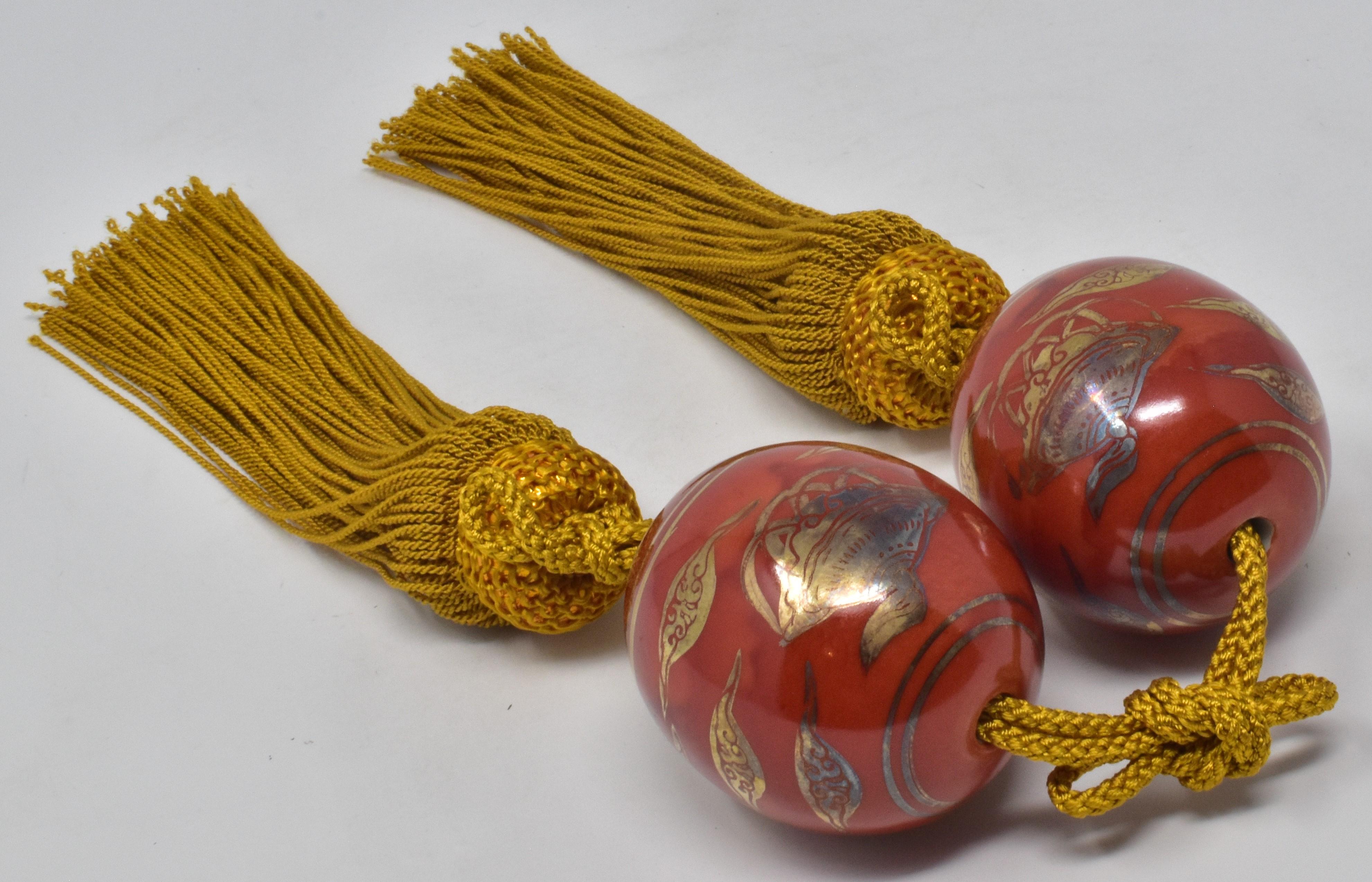 Pair of Japanese porcelain scroll weights (fuchin), intricately hand painted on a beautiful egg-shaped body in gold on an iron red background. This exquisite pair is from the Kutani region of Japan and each piece bears the mark of Kutani on the
