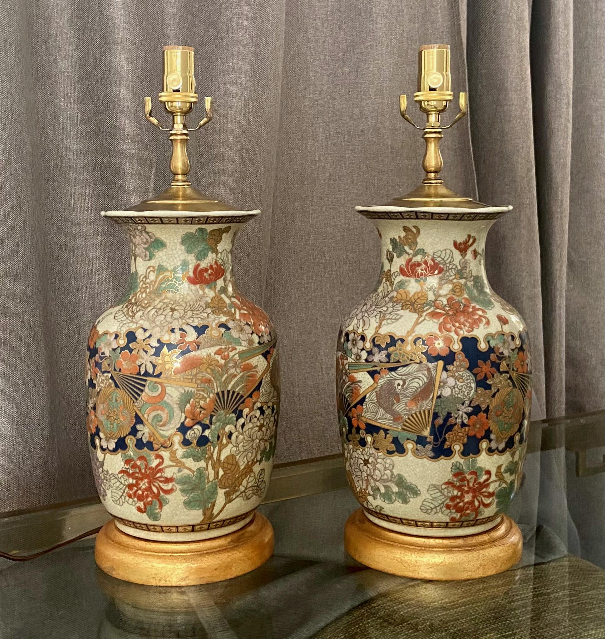 Pair of Japanese Satsuma crackle finish vases mounted on gilt turned wood lamp bases. The vases are expertly crafted with an overall crackle beige finish, and decorated with various hand painted flowers and 23k detailing. Newly wired with new brass