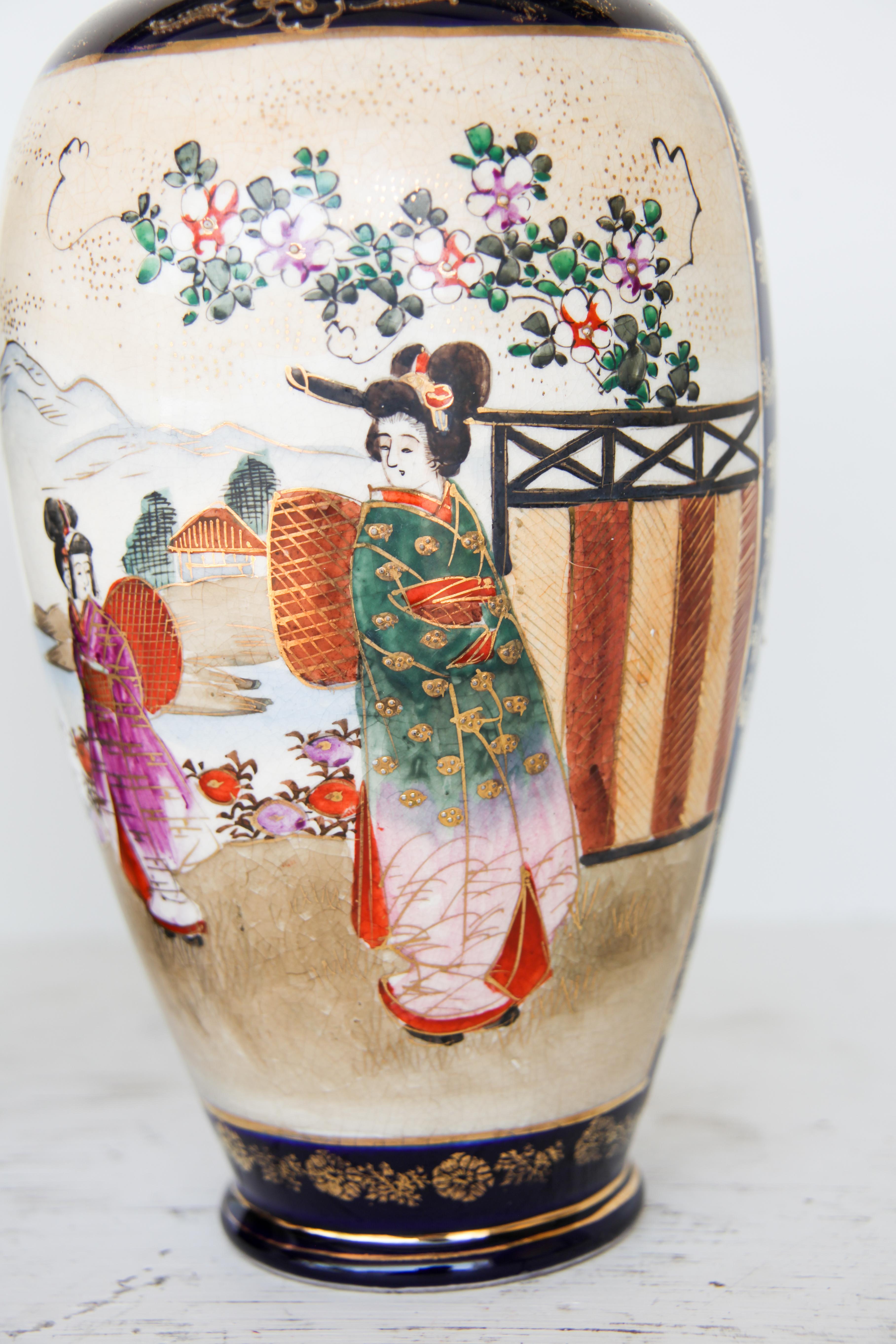 Pair of Japanese Satsuma Vases, with two scenes on each vase depicting Japanese women and children in landscape settings with mountains in the background. The vases have a cobalt ground color with gilt decoration