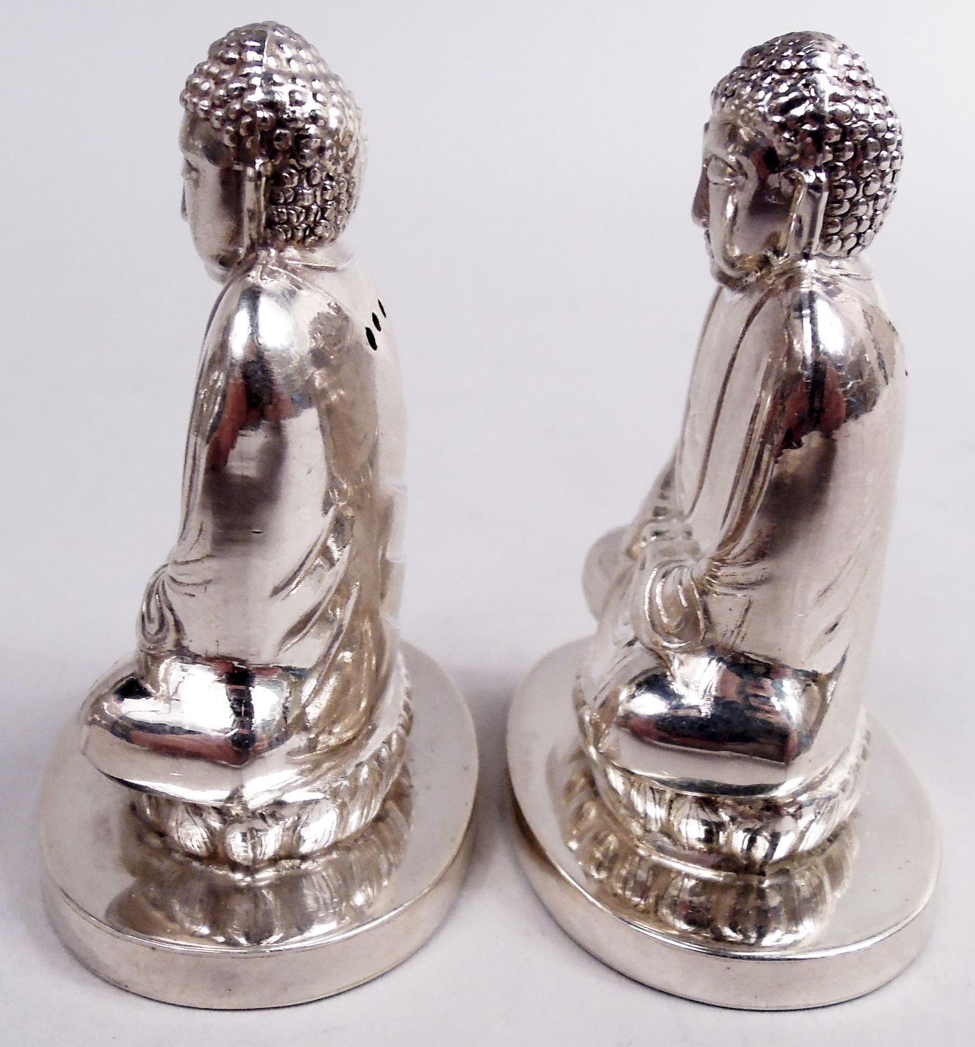 Pair of Japanese silver figural Buddha salt and pepper shakers, ca 1950. Each: Contemplative and cross-legged figure of the Zen-man himself. For a Siddhartha-serene dinner party. Pierced back. Underside has sliding hatch for filling. Marked