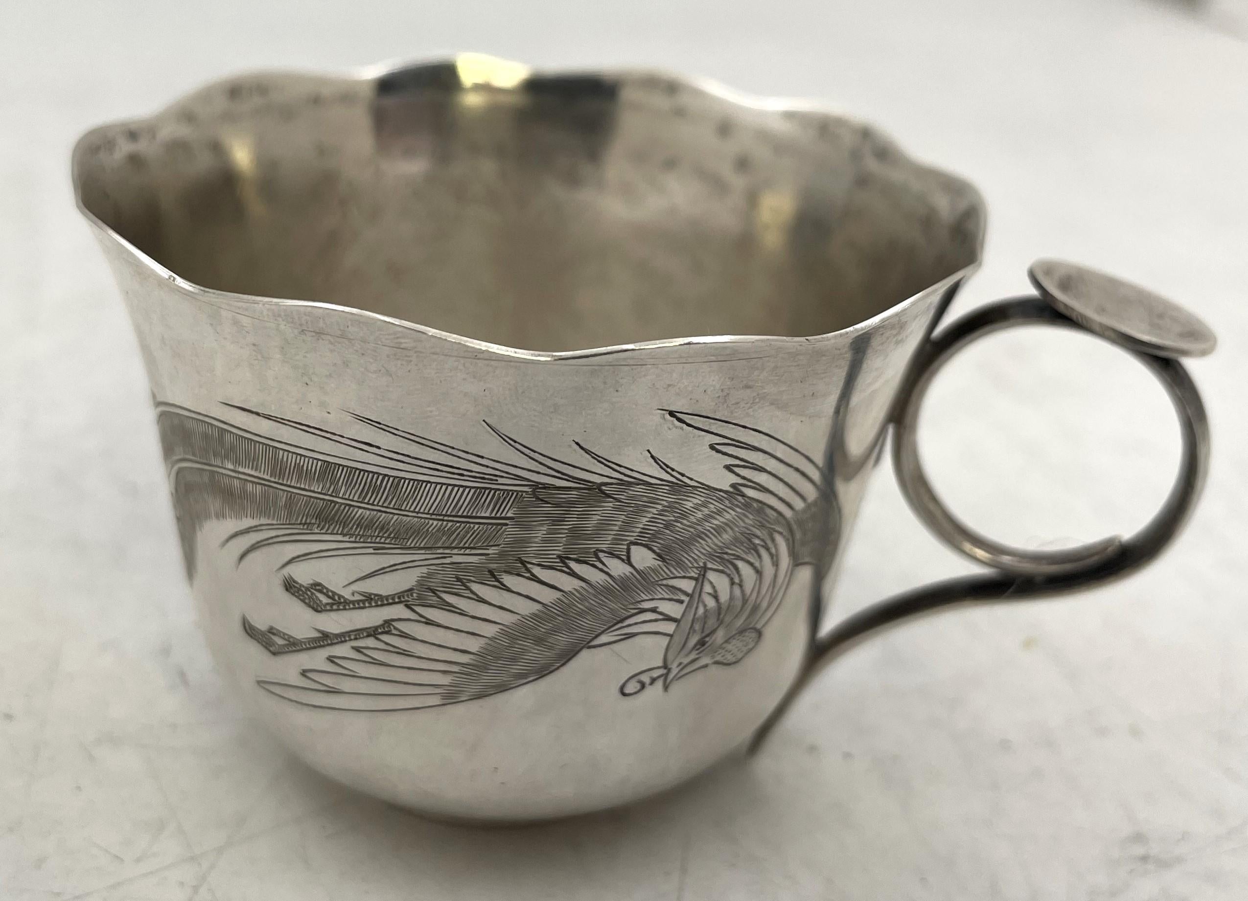 Pareja de tazas de té japonesas de plata, bellamente adornadas con motivos florales y pavos reales grabados. Miden 2 7/8'' de diámetro en la parte superior por 2'' de altura, pesan 5,1 onzas troy (158 gramos) y llevan los sellos que se muestran.

No
