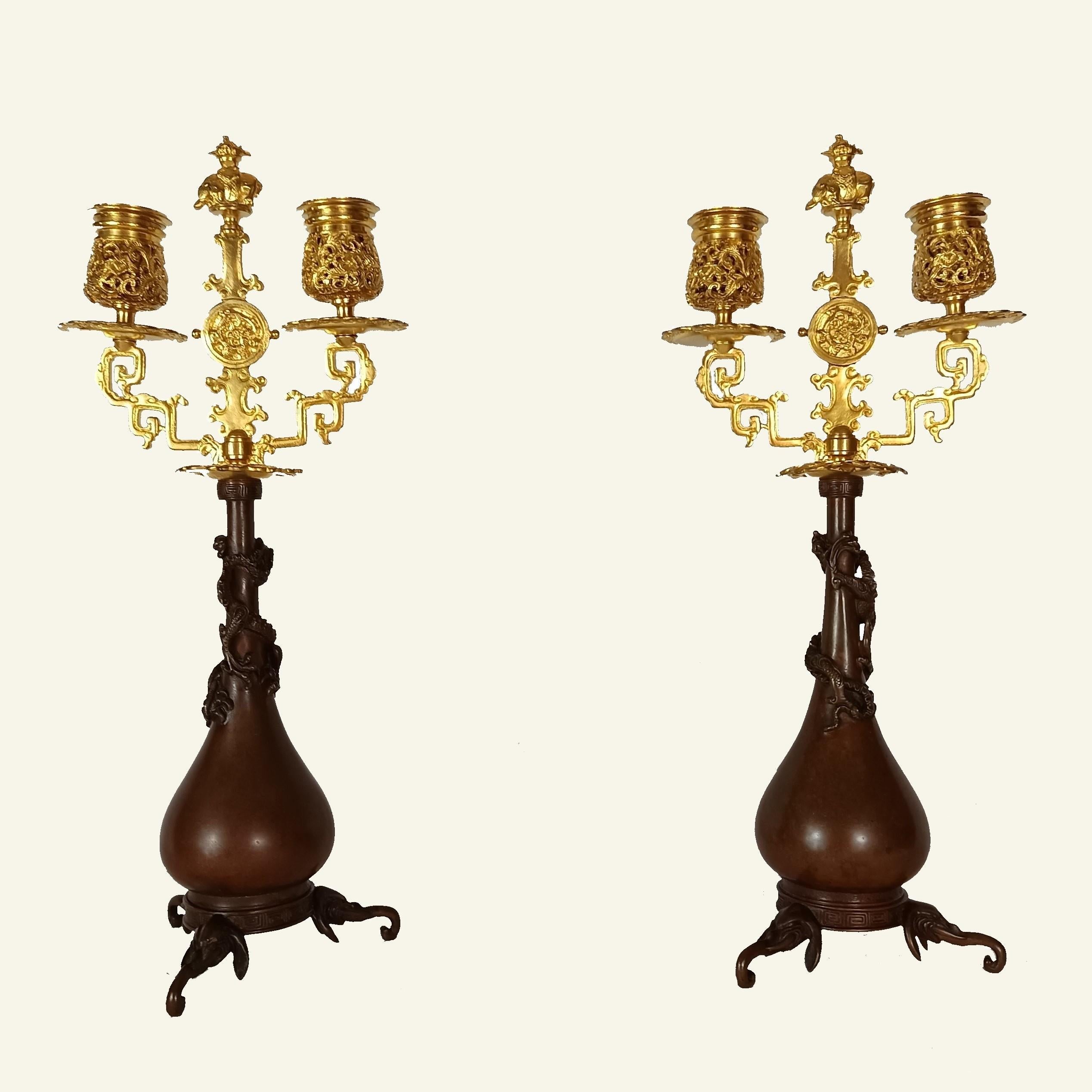 Exceptional pair of candlesticks with ovoid body and domed belly in chiseled bronze with brown patina on which a dragon coils, resting on tripod bases with 3 stylized elephant heads and a Chinese-style frieze.

The candlesticks themselves in the