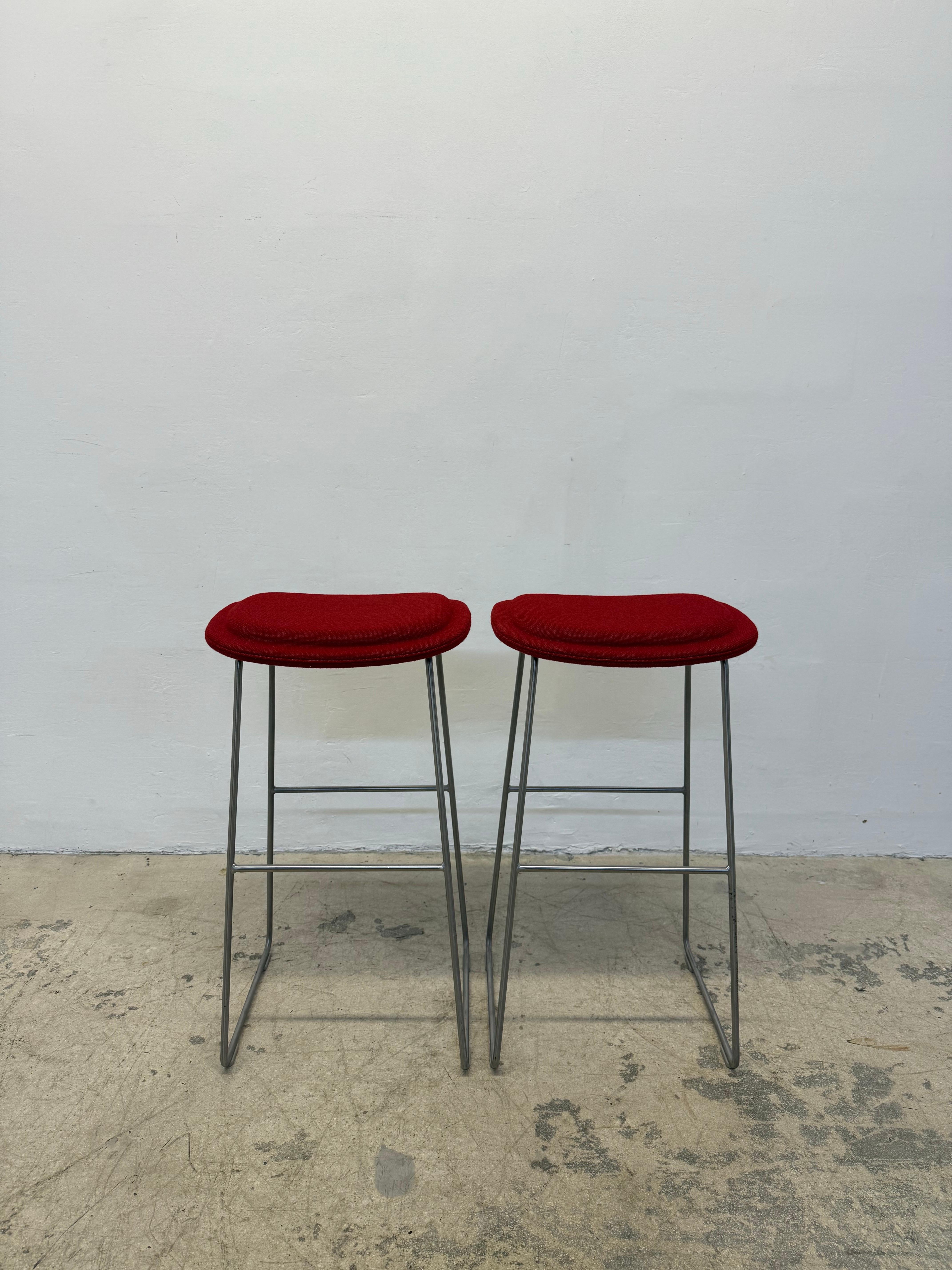 Pair of Hi Pad bar stools with foot rests designed by Jasper Morrison for Cappellini.  The Hi Pad stool features a seat in beech plywood padded with multi-density polyurethane foam on a satin stainless steel base. The red fabric is Hallingdal 2 -