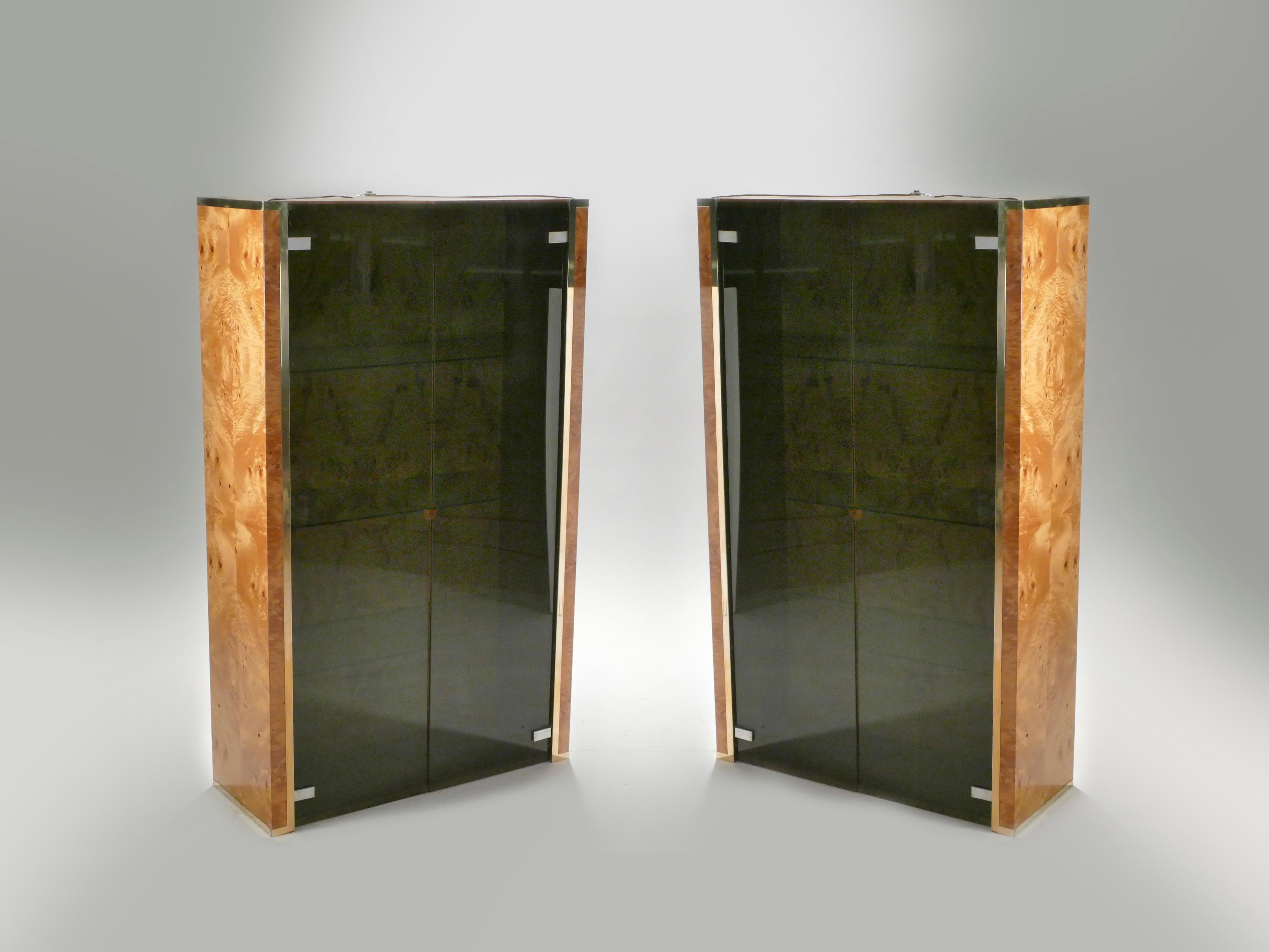 This bright vitrine was designed by Jean-Claude Mahey and is typical of his 1970s work. The body of the piece is made from sunny, caramel-colored burlwood, and the doors are a fine glass. A brass border runs along the bottom of the piece, giving it