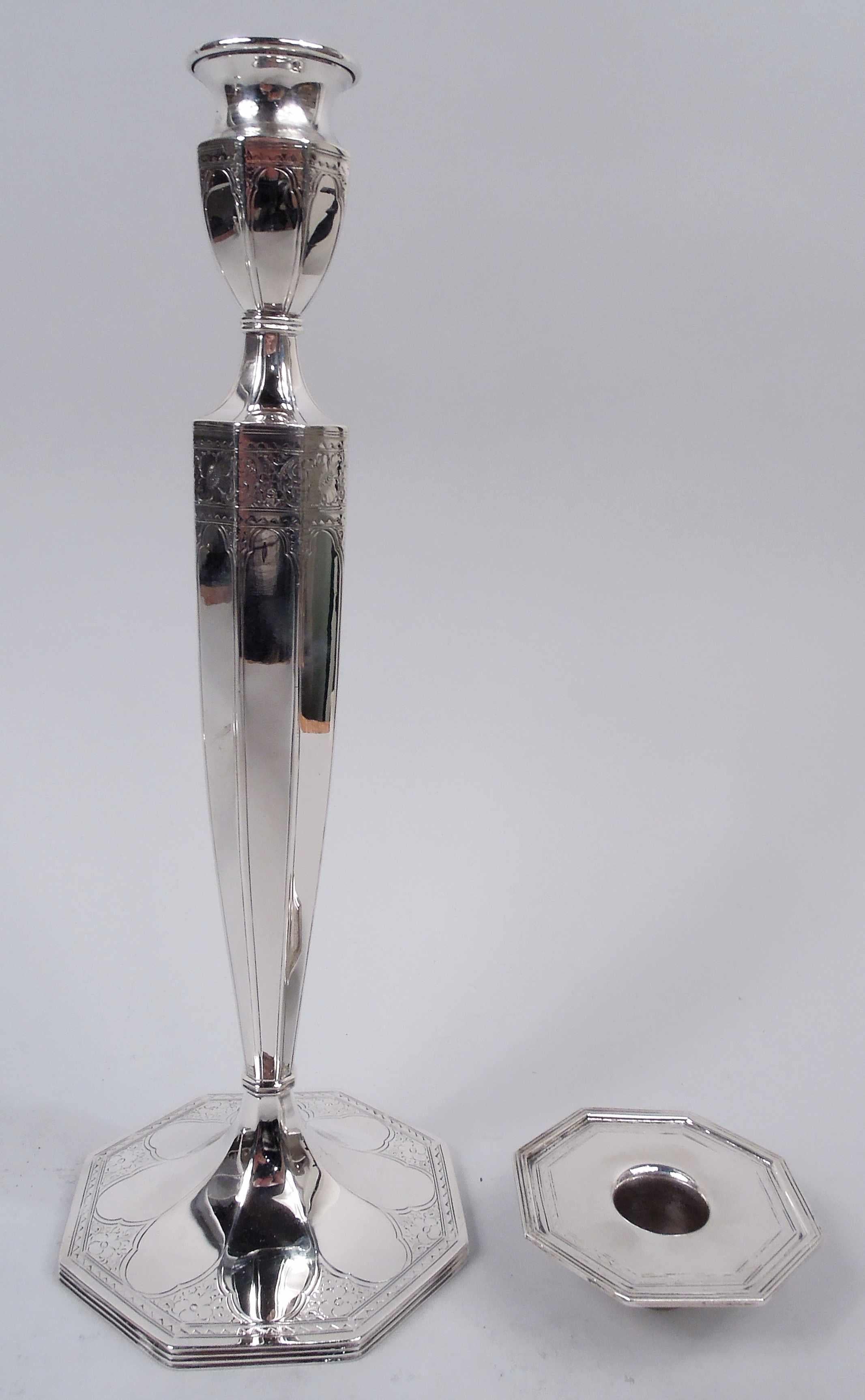 Pair of Edwardian Classical sterling silver candlesticks. Made by Barbour Silver Co. (part of International) in Hartford, ca 1910. Each: Tapering socket with flat and detachable bobeche; raised foot. Faceted. Engraved floral and zigzag bands. Lobed