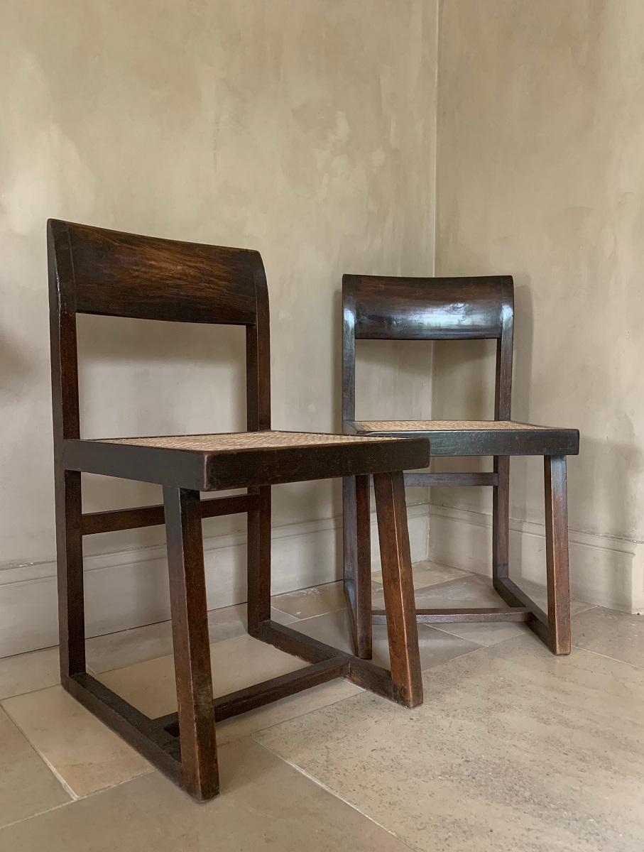 A good authentic set of two Chandigarh chairs. Artisanally and locally made with pegged solid teak and braided canework in the 1960s. This type is known as the box chair. The asymmetric “frame” is beautifully complemented with the convex 'banner'