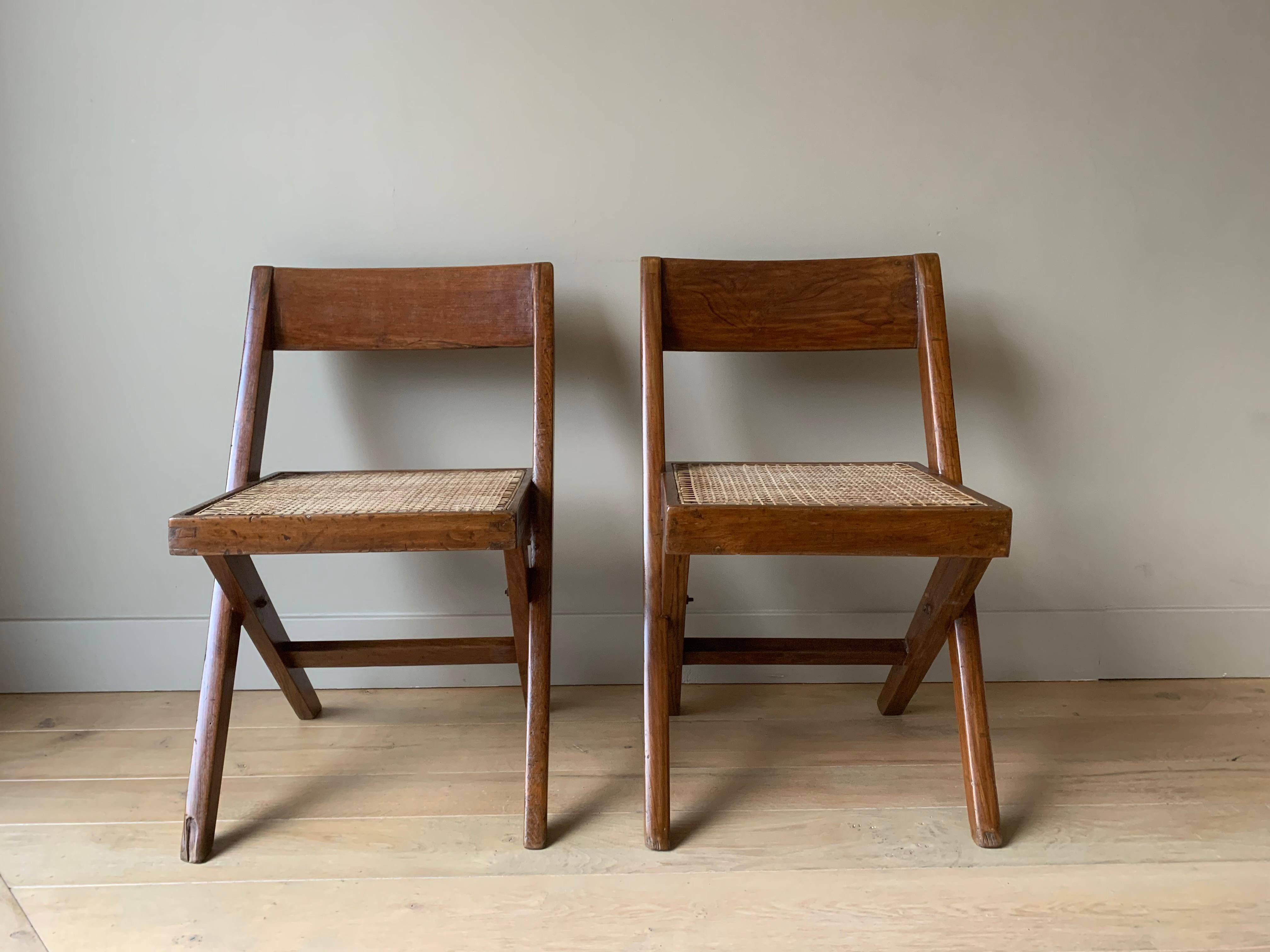A good authentic set of two Chandigarh chairs. Artisanally and locally made with pegged solid teak and braided canework in the 1960s. This type is known as the Library chair. The x- “frame” is beautifully complemented with the convex 'banner' type