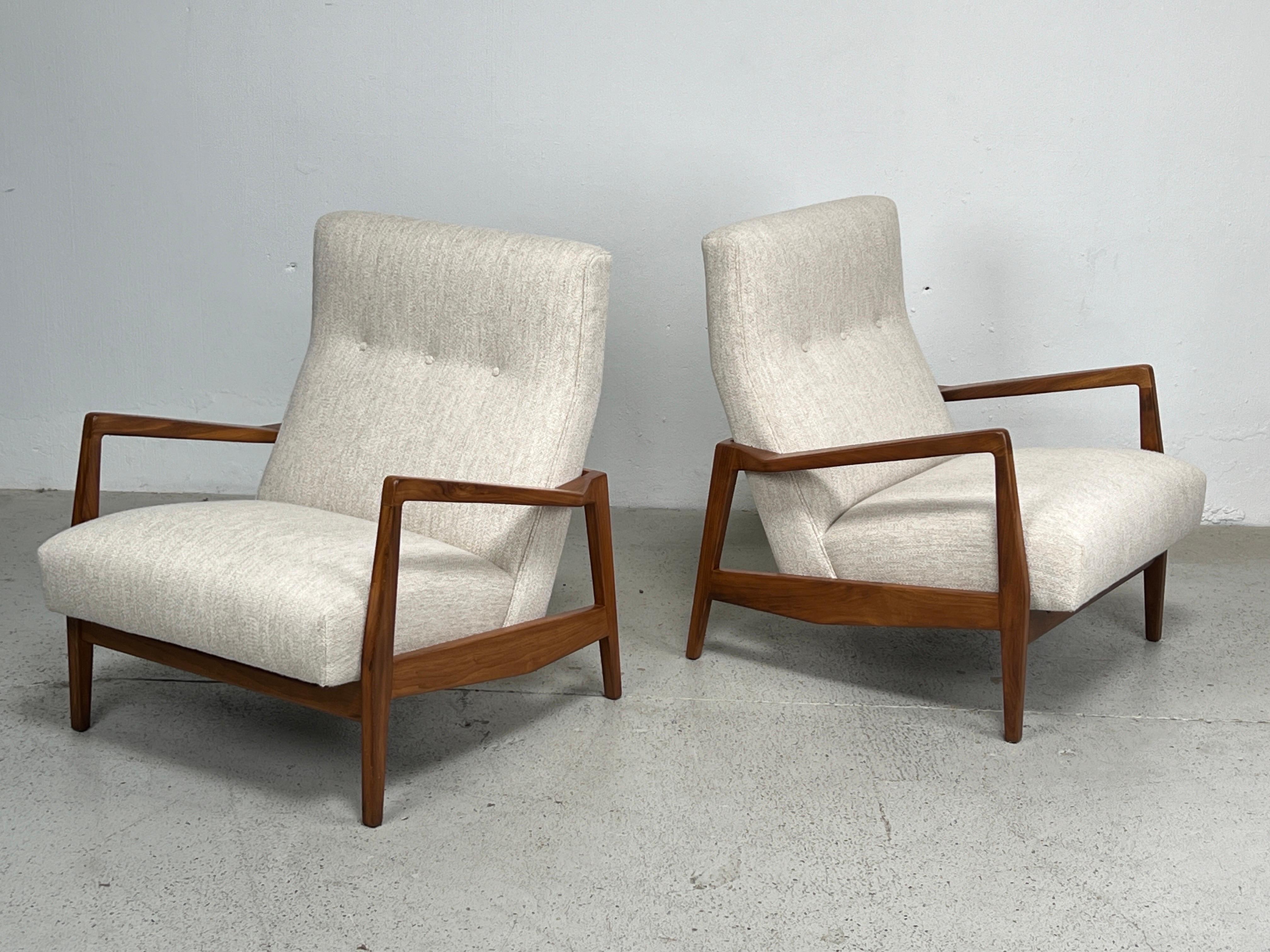 A pair of solid walnut lounge chairs designed by Jens Risom. Fully restored and reupholstered in Holly Hunt fabric. 