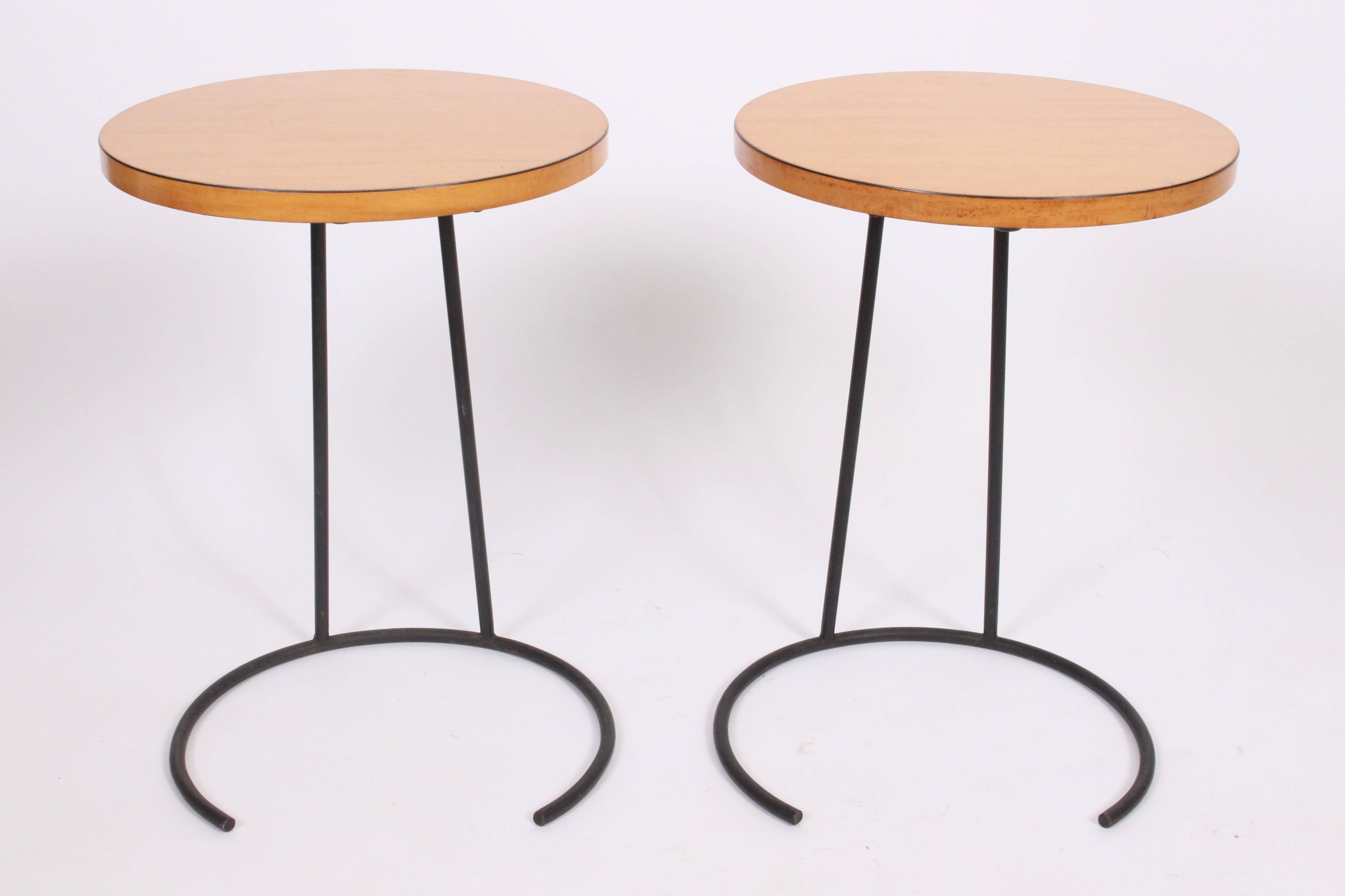 Early pair of small Jens Risom stacking birch occasional tables. Smaller circular table with knife-edge birch laminate top cantilevered on black enameled wrought iron base. Versatile. Compact. Small footprint. Front of sofa. Maker's label to base.
 