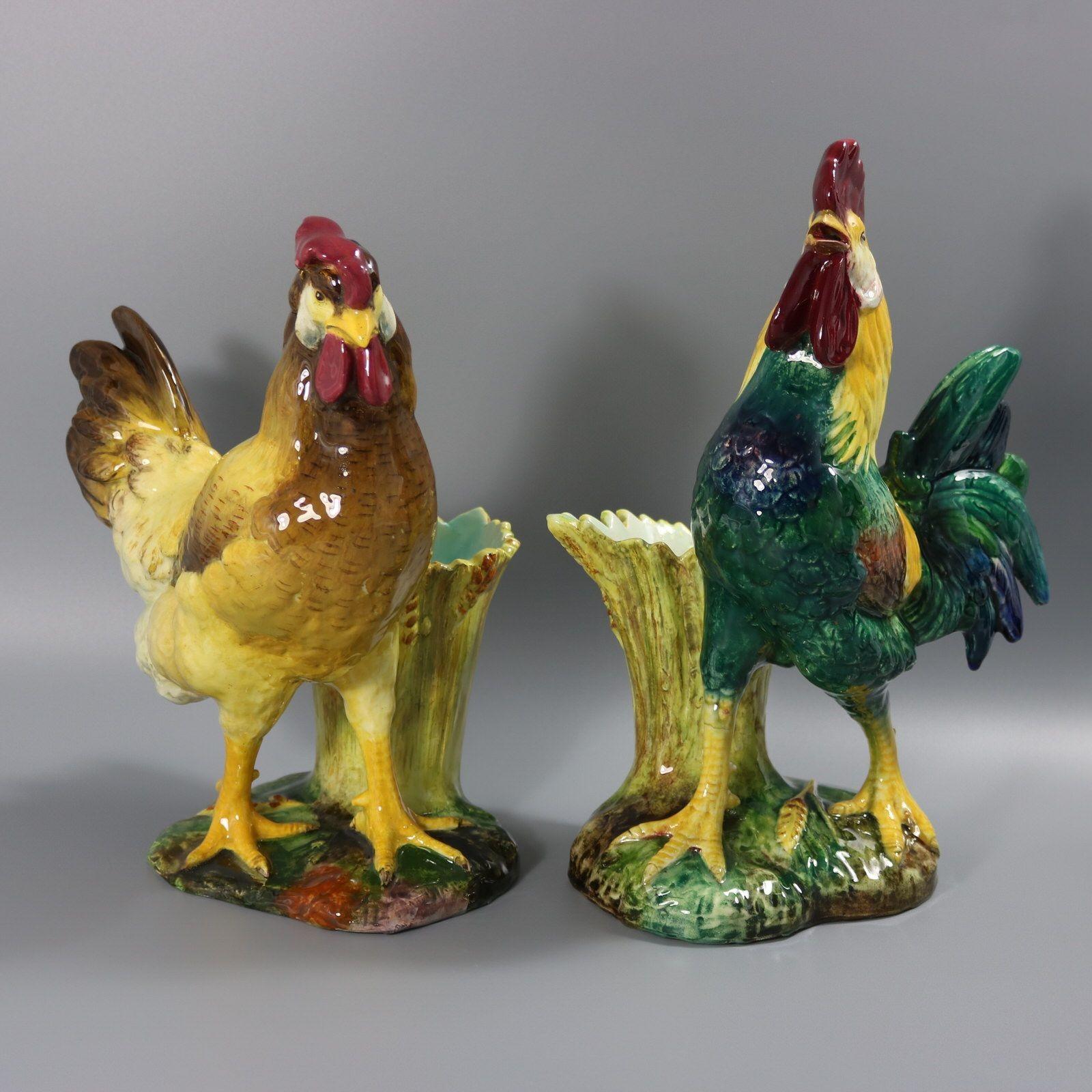 Coppia di vasi figurati in maiolica francese di Jerome Massier che raffigurano una coppia di galline - un gallo e una gallina - davanti a recipienti per il pane di grano. Colorazione: predominano il giallo, il blu acqua e il marrone scuro. Il pezzo