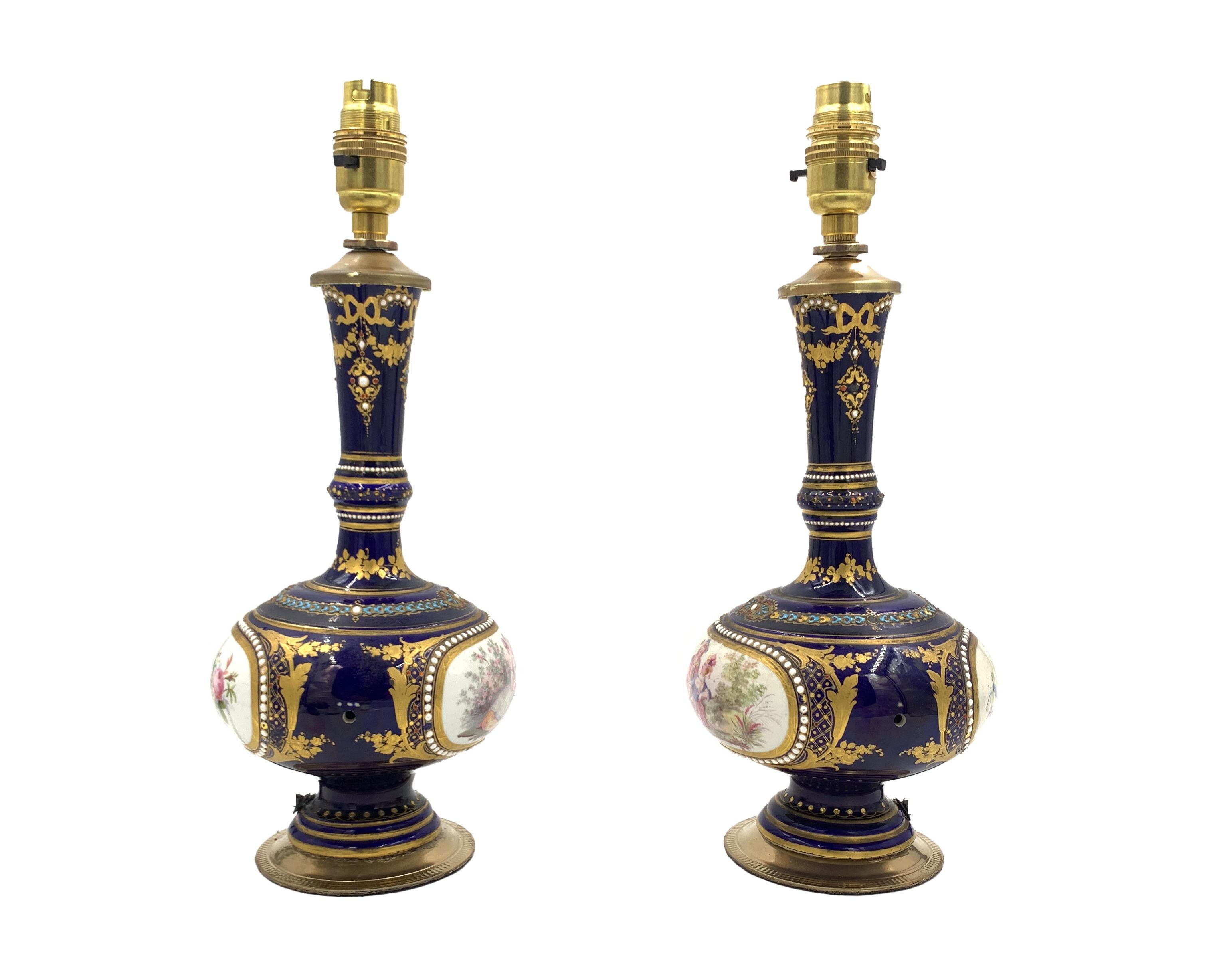 Beautifully gilded, enamelled and jewelled porcelain table lamps, The front panel on each is hand painted to represent a romantic scene while the reverse panel depicts still life painting of flowers and fruits.
 