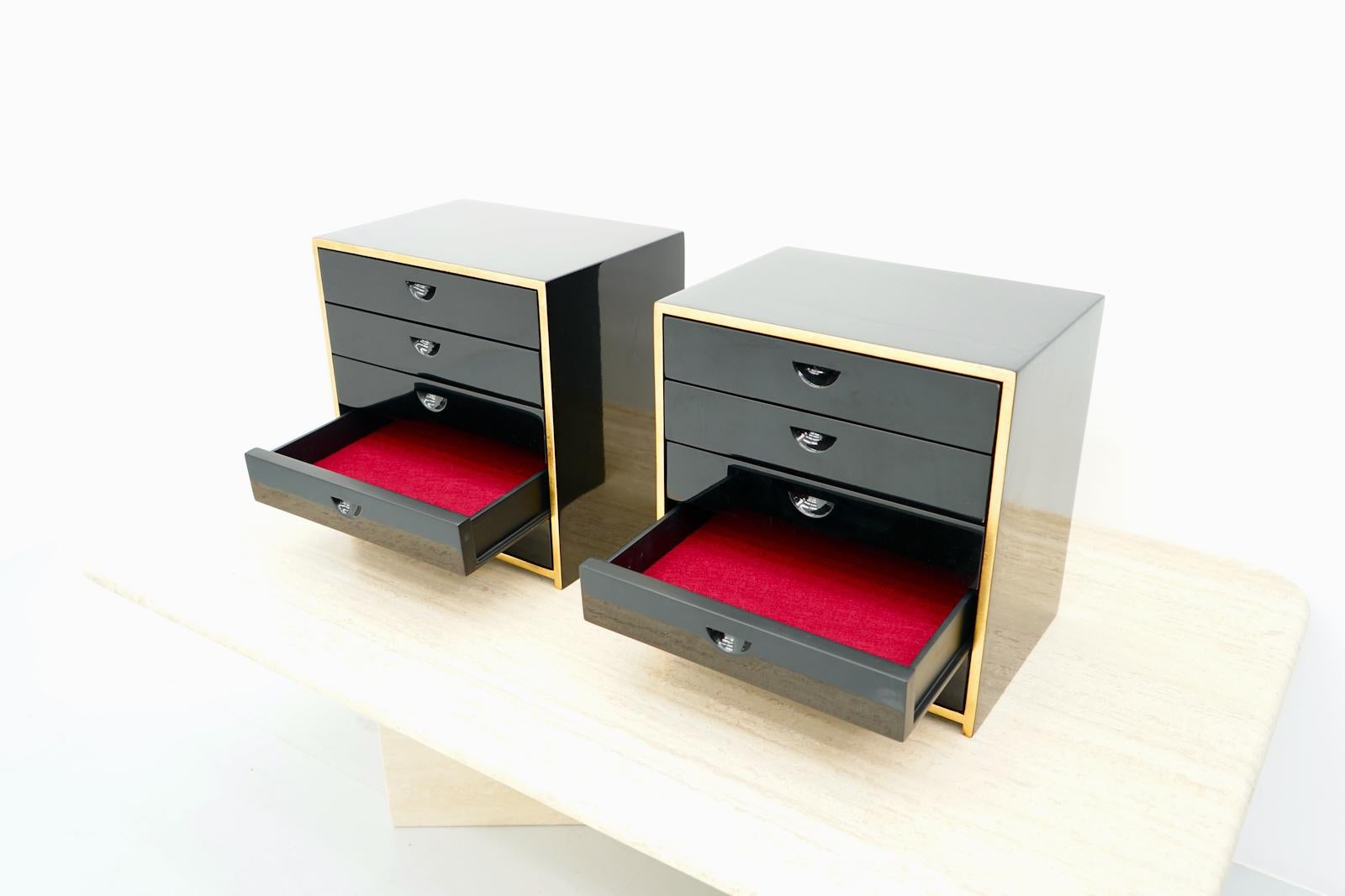 A pair of jewelry cabinets with each five drawers. The cabinets are glossy black lacquered and are lined with red felt on the inside. The outer edge is oversightwith gold leaf. Very high quality workmanship. Very good condition. 
The cabinets were