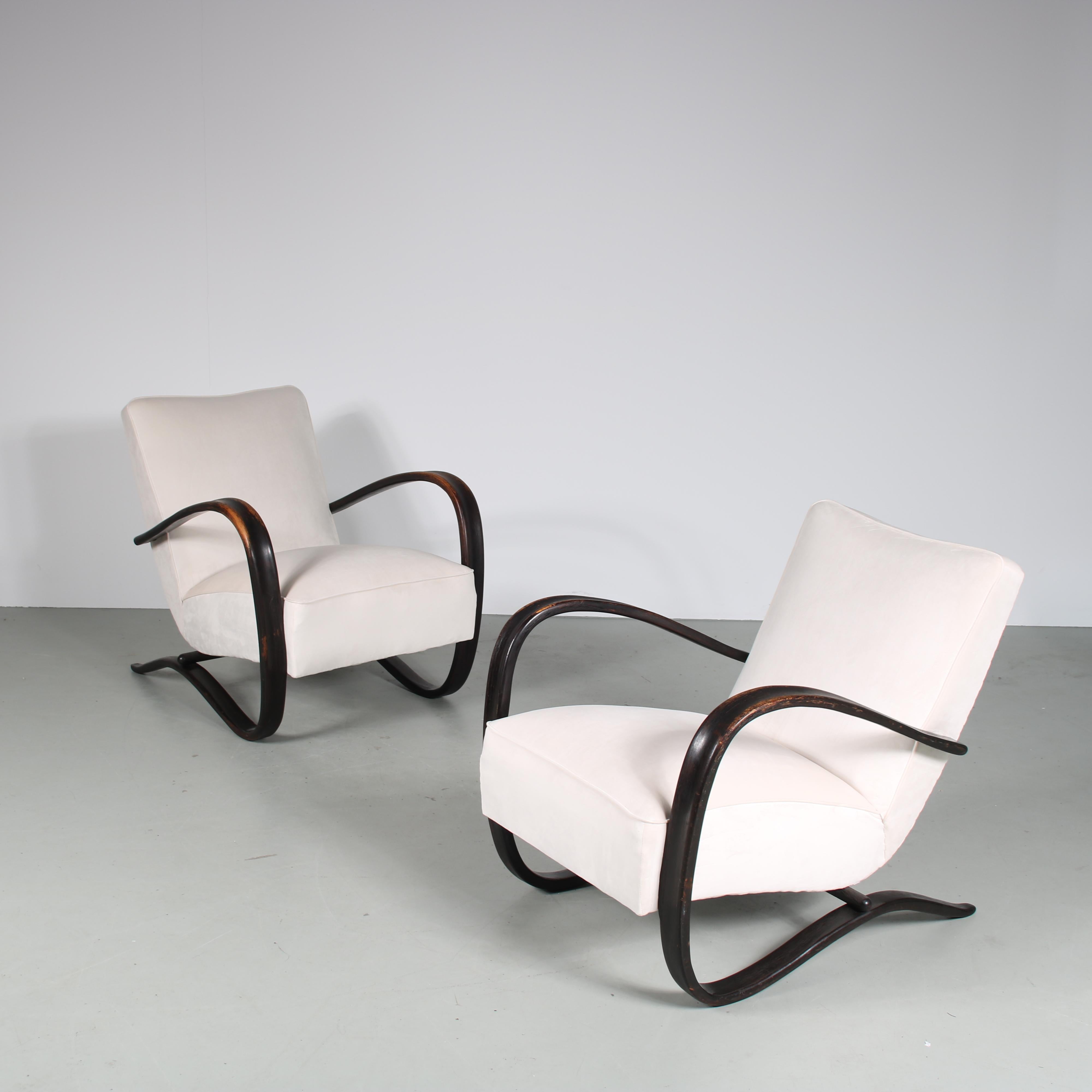 A stunning pair of lounge chairs in eye-catching Czech design by Jindrich Halabala, manufactured by Up Zavody in the Czech Republic around 1930.

These chairs have a beautiful Art Deco style. The very dark wooden curved armrests transition