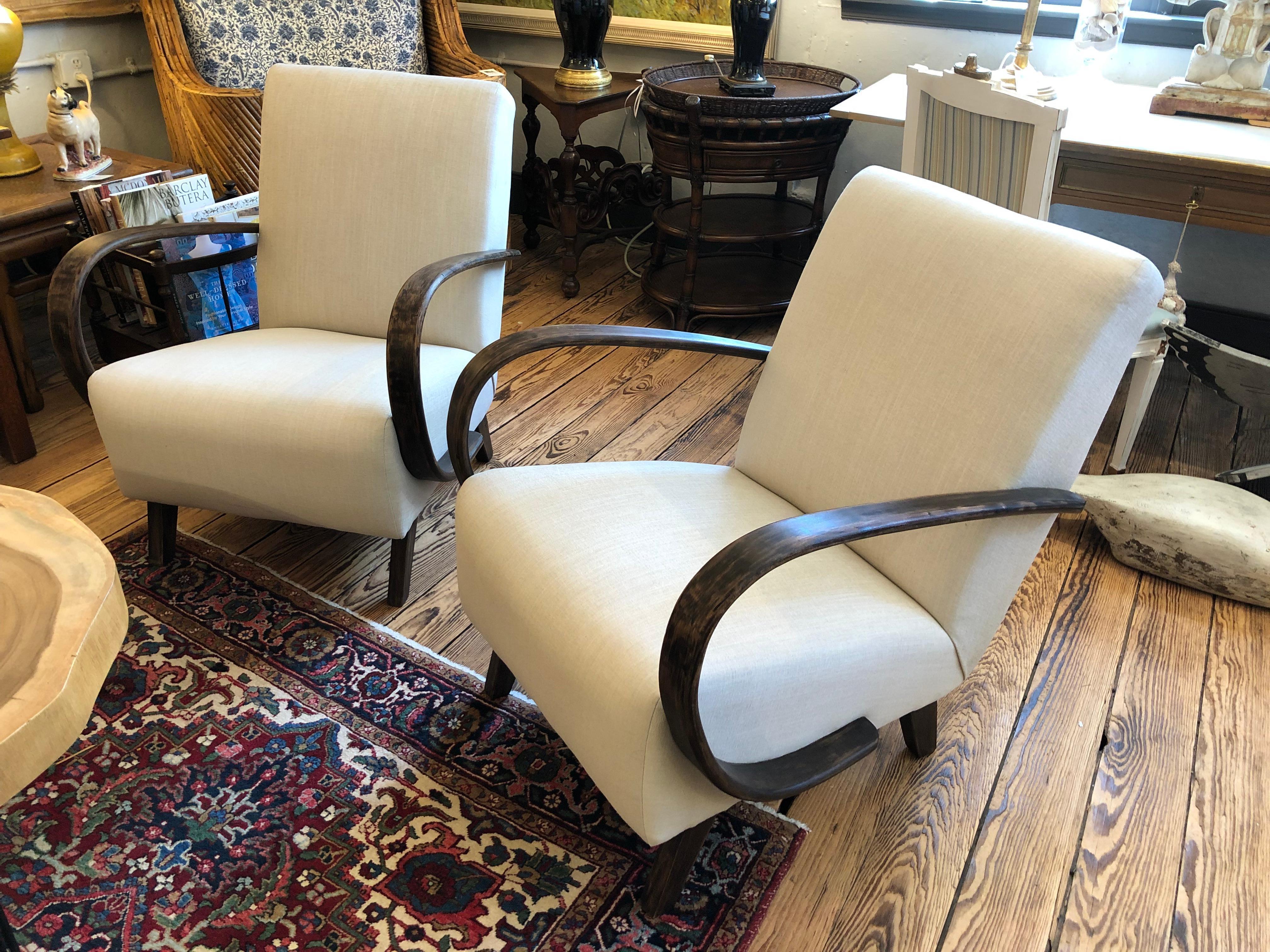 Superb comfortable sophisticated pair of vintage club chairs by Czech designer Jindrich Halabala having a deep upholstered linen seat resting on angled ebonized feet framed by dramatically curved bentwood arms. A blend of Art Deco and Modern make