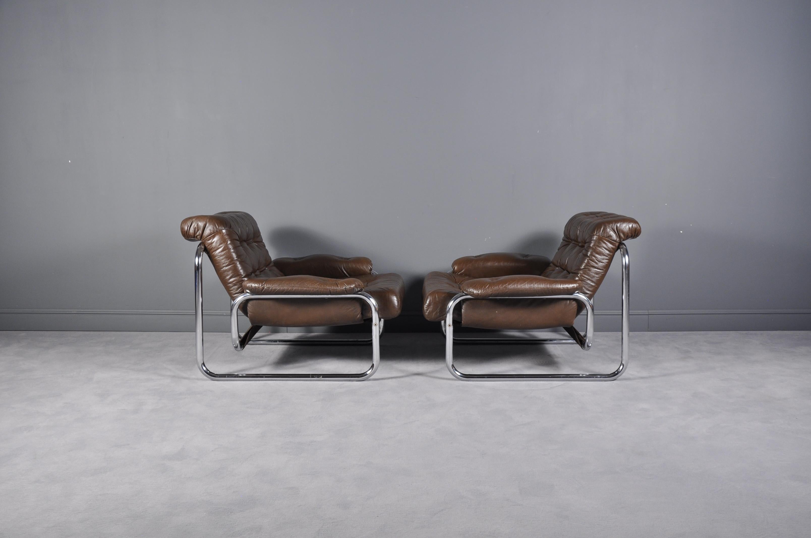 Pair of Swedish 1970s tubular metal framed lounge chairs with original brown tufted cushion and arm rests. Produced by Ikea, model Troligen, designed by Johan Bertil Häggström.
 