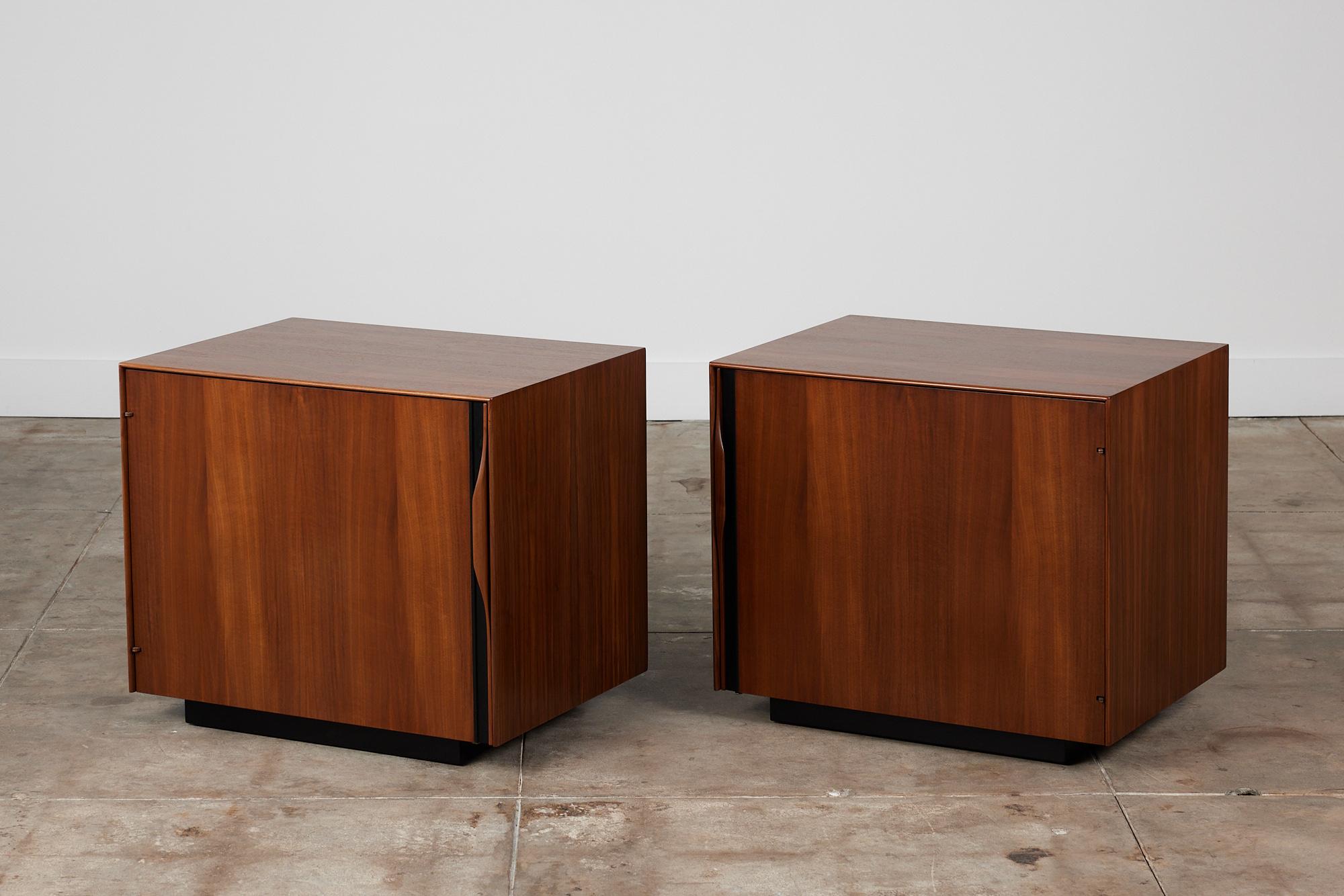 Pair of walnut nightstands by John Kapel for Glenn of California, circa 1960s, USA. The nightstands each feature a single door front with sculpted handles and black linear detailing. The hinged doors open to reveal magazine storage on the door