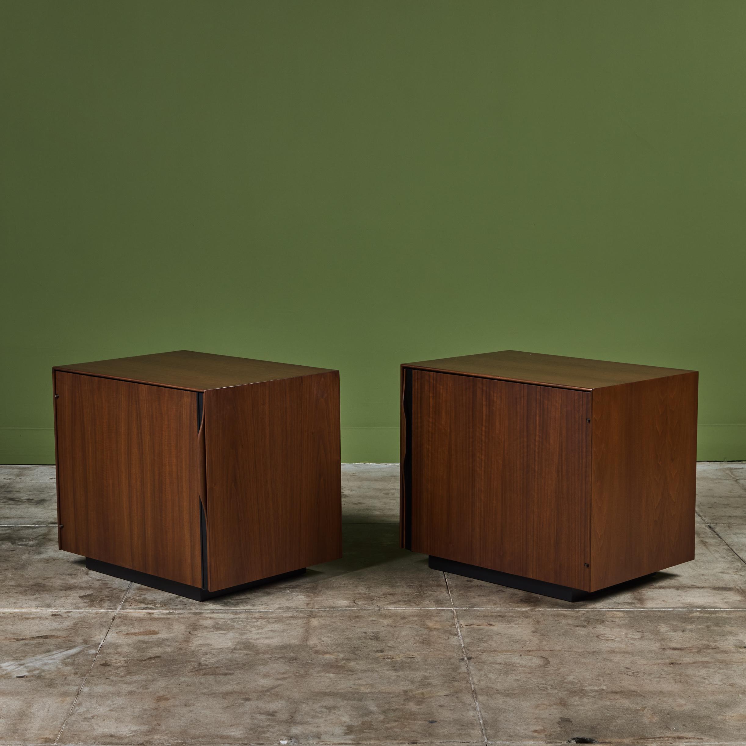 Pair of walnut nightstands by John Kapel for Glenn of California, c.1960s, USA. The nightstands each feature a single door front with sculpted handles and black linear detailing. The hinged doors open to reveal magazine storage on the door panel.