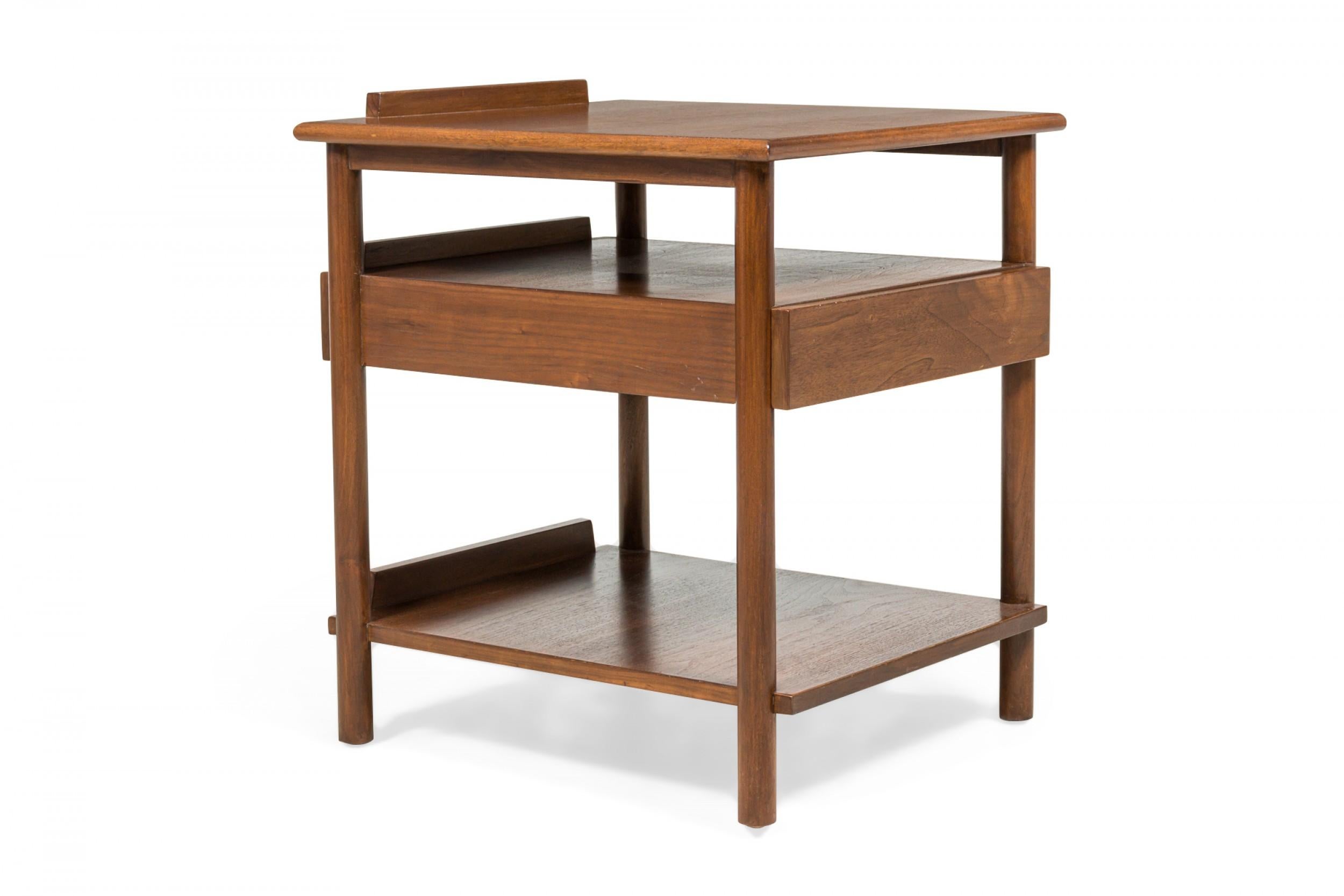 Pair of American mid-century walnut end / side tables with dowel legs supporting an open design structure with a rectangular table top, single drawer, and lower stretcher shelf. (John Stuart)(Priced as Pair).
  