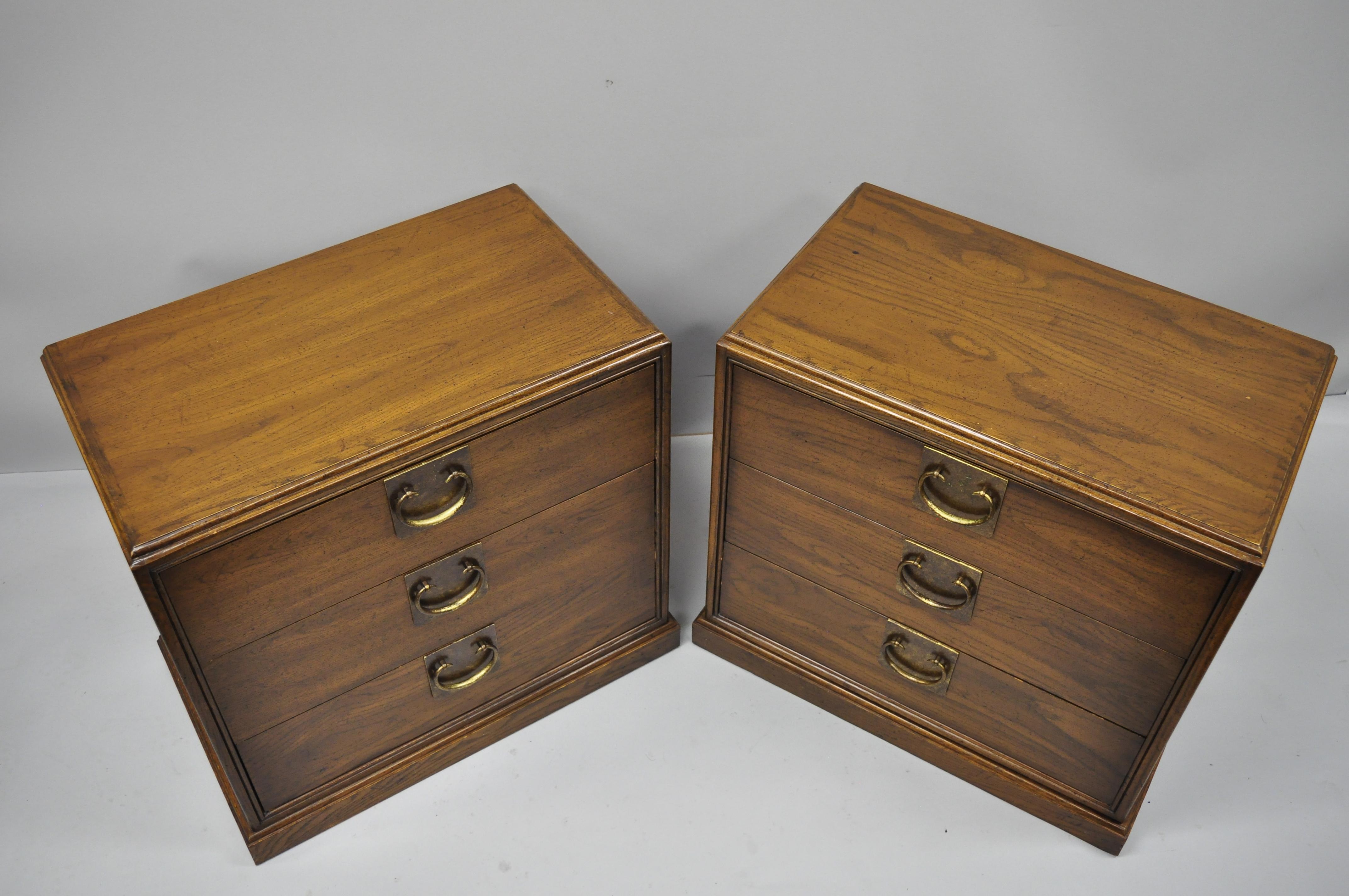 Pair of John Stuart chinoiserie James Mont style oak nightstand bedside chests. Items feature solid wood construction, beautiful wood grain, original label, 3 drawers, solid brass hardware, clean modernist lines, circa 1960. Measurements: 25