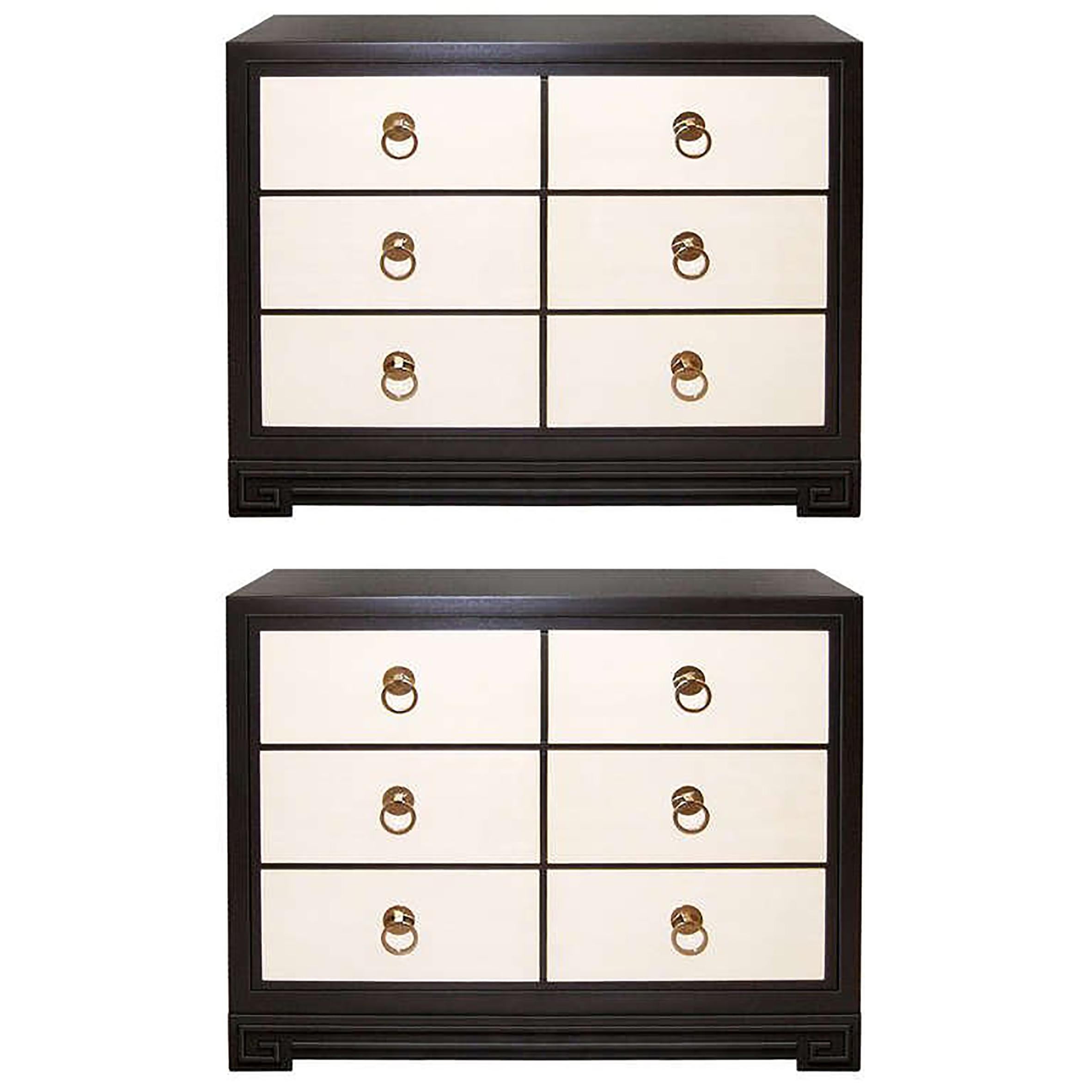 A pair of 3 drawer ebonized mahogany dressers with parchment covered drawer fronts and brass pulls. Base of dresser have raised Greek key motif by John Stuart, American C. 1940's