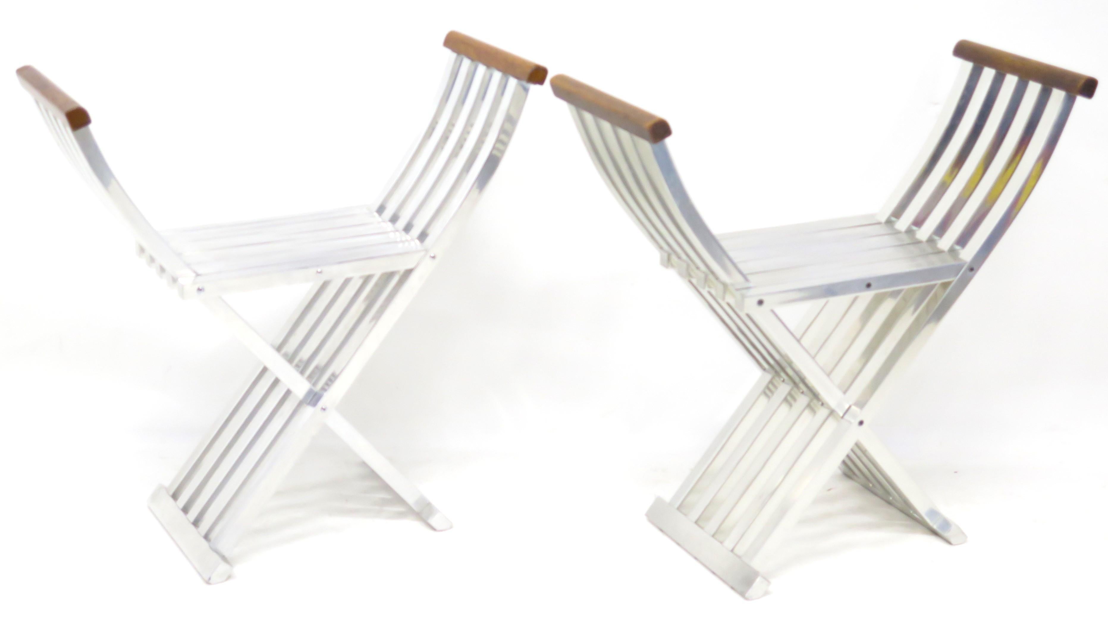 pair of designer John Vesey's (American, 1925-1992) classic folding benches / stools / curule seats in brushed aluminum with wood (walnut) armrests inspired by the Savonarola chair of the Middle Ages, United States, mid-century, circa