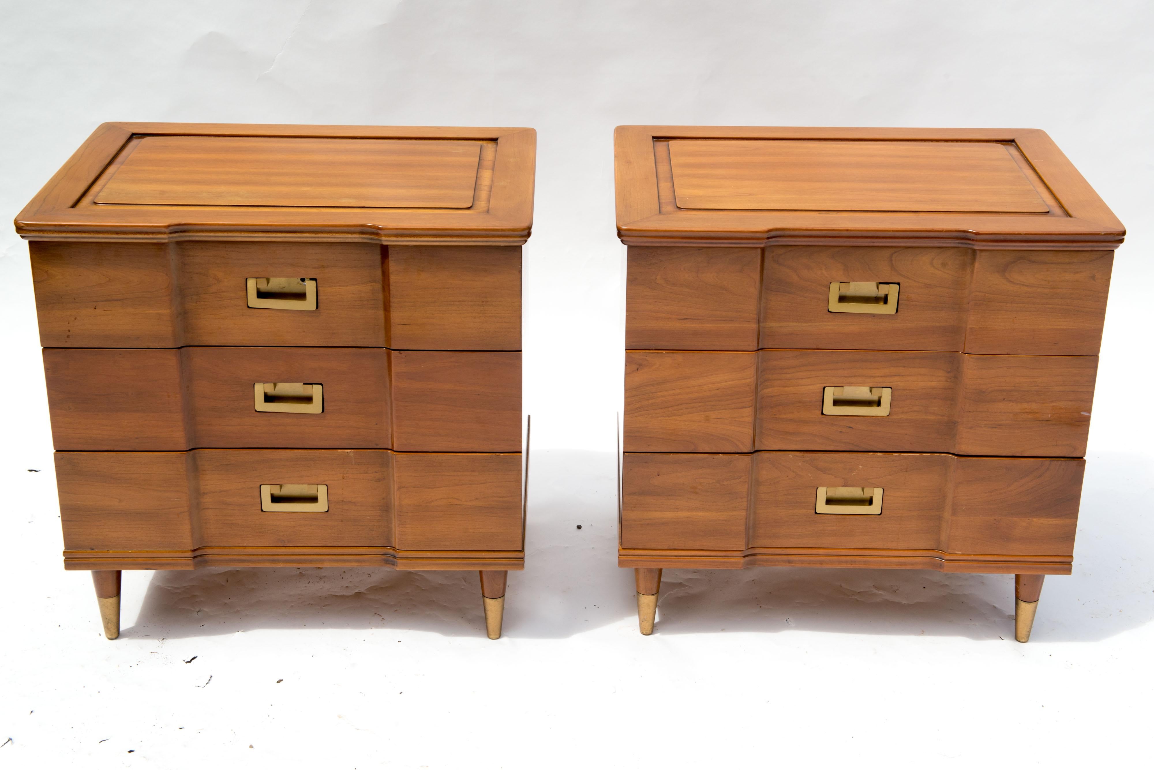 An exceptional pair of Mid-Century Modern John Widdicomb three drawer nightstands. Made of solid cherry wood with solid brass drawer pulls and tapered capped brass feet. The backs of these cabinets are finished, allowing them to stand free in any