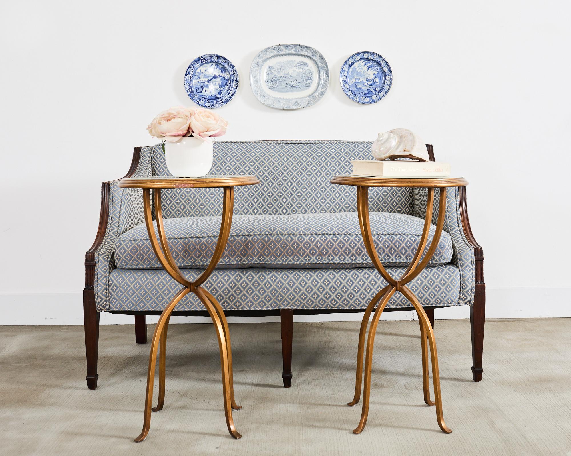 Elegante paire de tables rondes pour boissons ou tables d'appoint conçues par Jonathan Charles. Les tables présentent un cadre en fer avec des pieds en fer à cheval gracieusement incurvés supportant un plateau rond. Le plateau a un bord en escalier