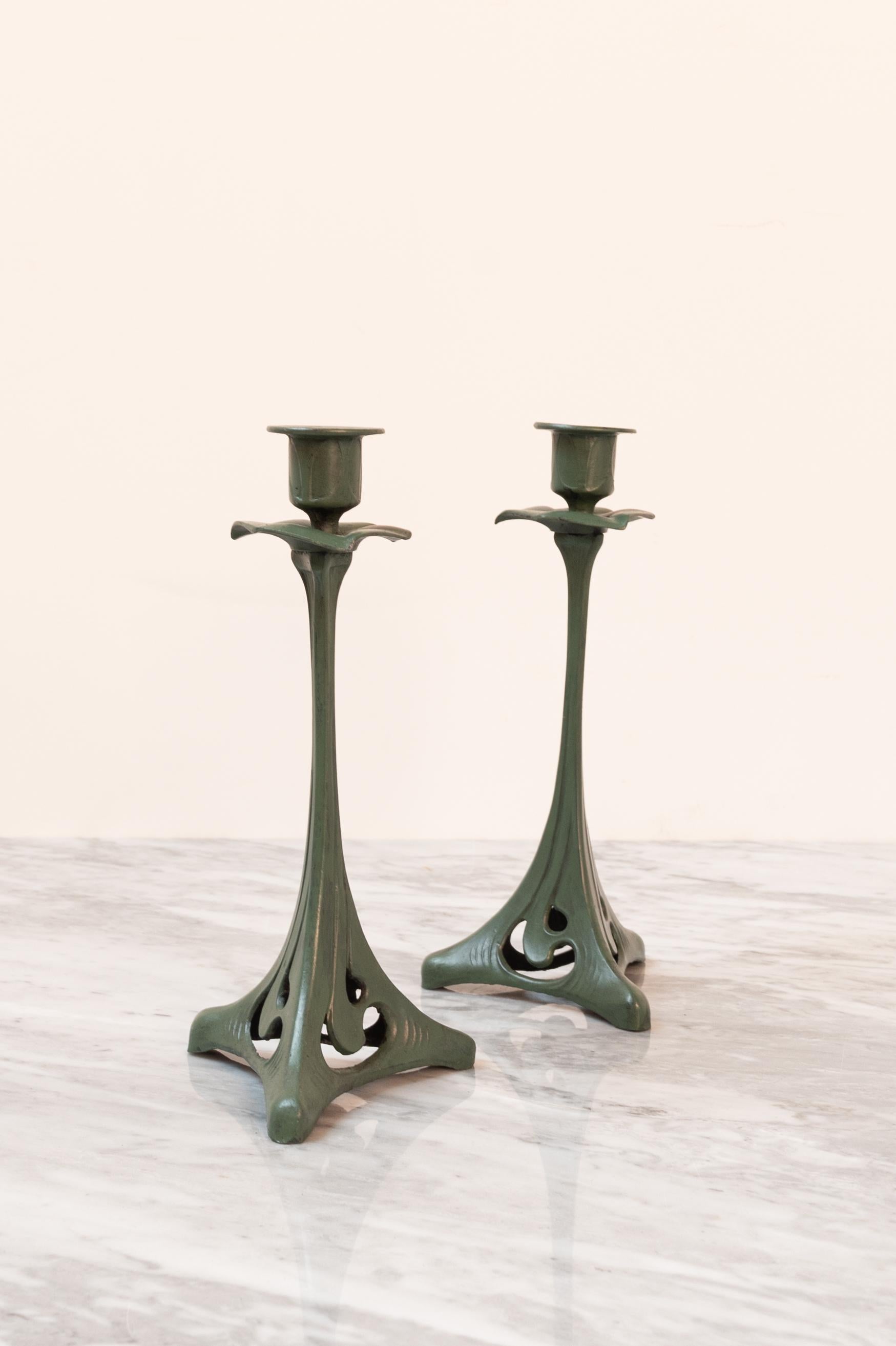 Presumably in bronze. The candle holders have a great green patina.

H 20,5 cm x 9,5 cm (foot)