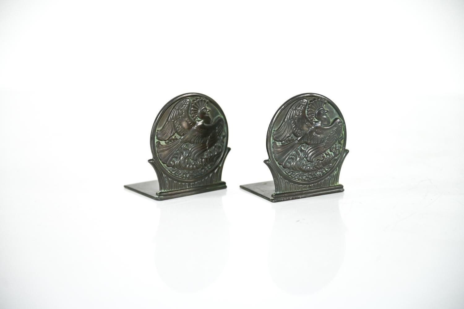 Magnifique paire de serre-livres danois du début du XXe siècle en bronze patiné, conçus par Just Andersen. Ces serre-livres sculpturaux en forme de disque en 