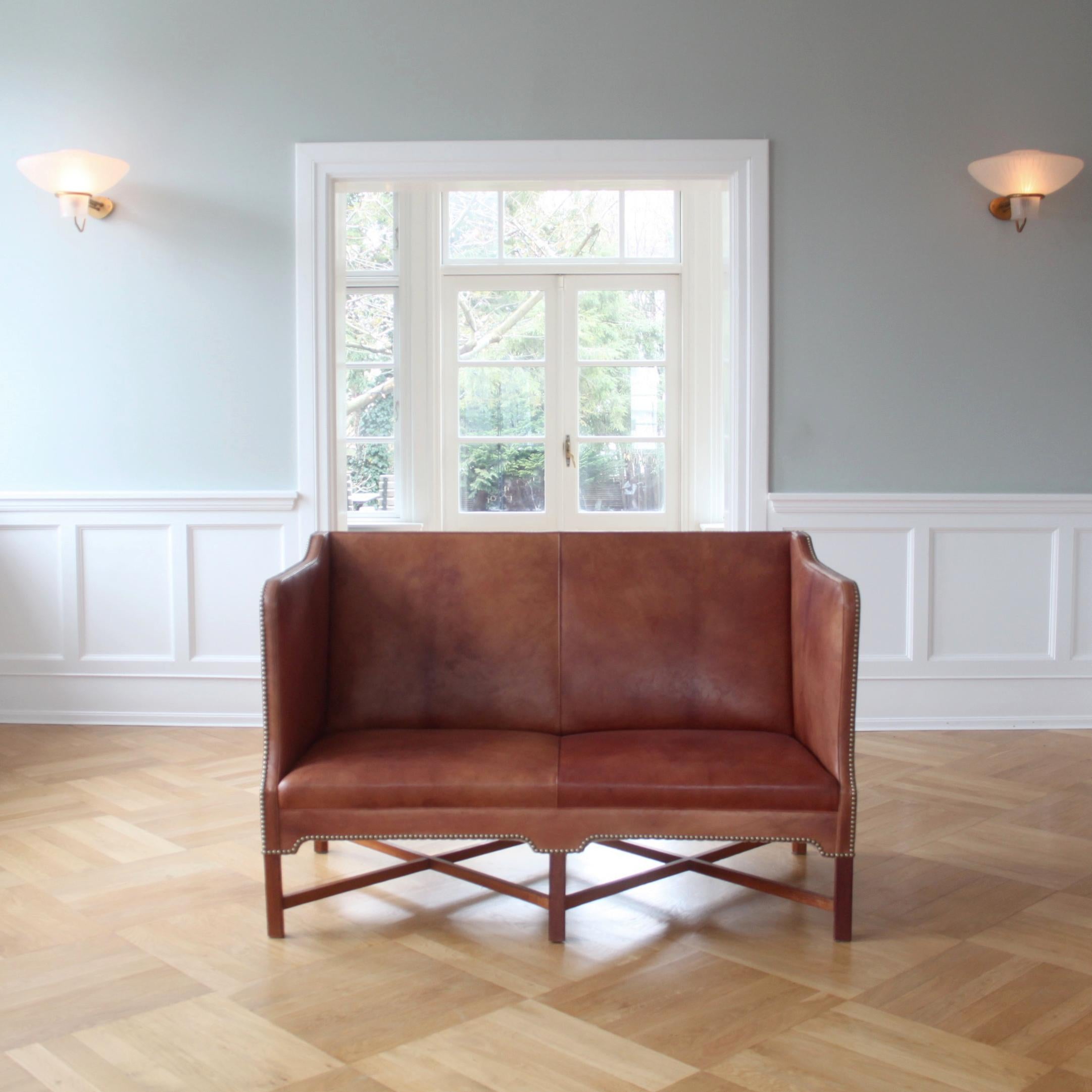 Kaare Klint & Rud Rasmussen snedkerier.

A stunning pair of rare Kaare Klint Model no. 4118S two-seater box-shaped sofas with profiled cross legged mahogany frame. (Also called X-Base Sofas). 
Designed in 1930 for the Ny Carlsberg Foundation,