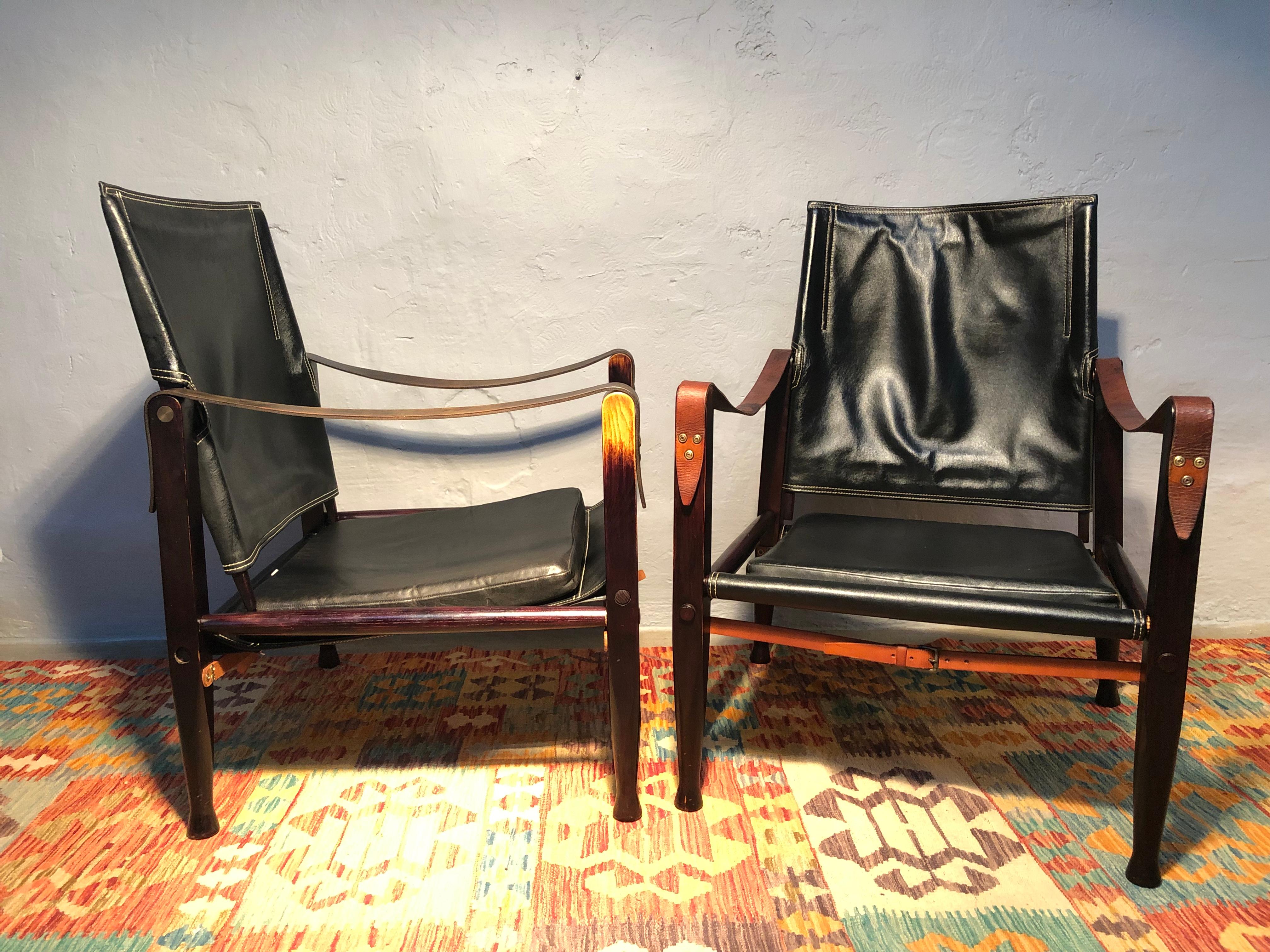 A pair of safari chairs designed by Kaare Klint for Rud Rasmussen furniture makers of Copenhagen in great original condition.
Kaare Klint designed the safari chairs in 1933.
These iconic chairs are made of black stained ash and leather. 
They have
