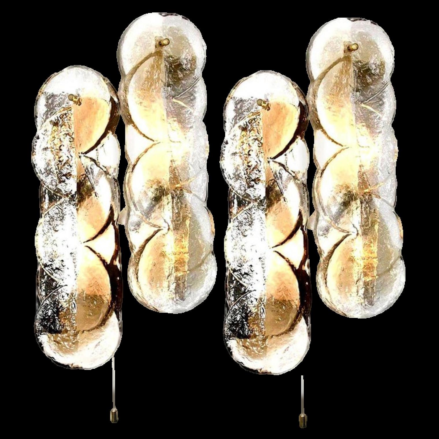 Ein Paar Kalmar Swirl Wandleuchten mit klaren Glasscheiben und hellen, bernsteinfarbenen Goldfischstreifen. Das schöne, dicke, strukturierte Glas wird durch weiße Metallbeschläge ergänzt. Schöne Messingknöpfe. In ausgezeichnetem Zustand.

Jeder