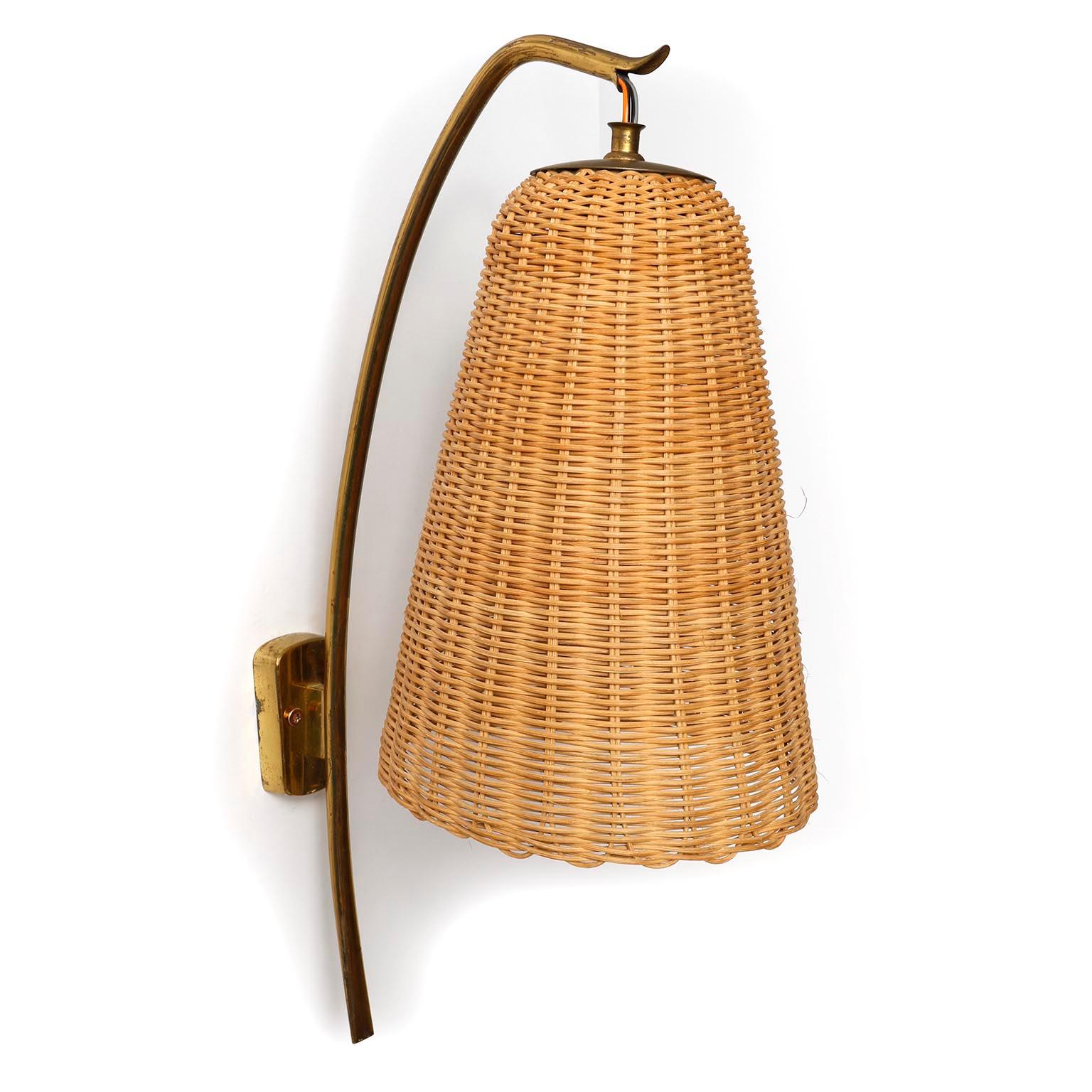 A pair of rare wall lamps model 'Soldanella', no. 4331/1 by J.T. Kalmar, Vienna, Austria, manufactured in midcentury, circa 1960 (1950s or early 1960s).
A wickerwork lamp shade on a cord and patinated brass arm.
The wicker is in excellent original