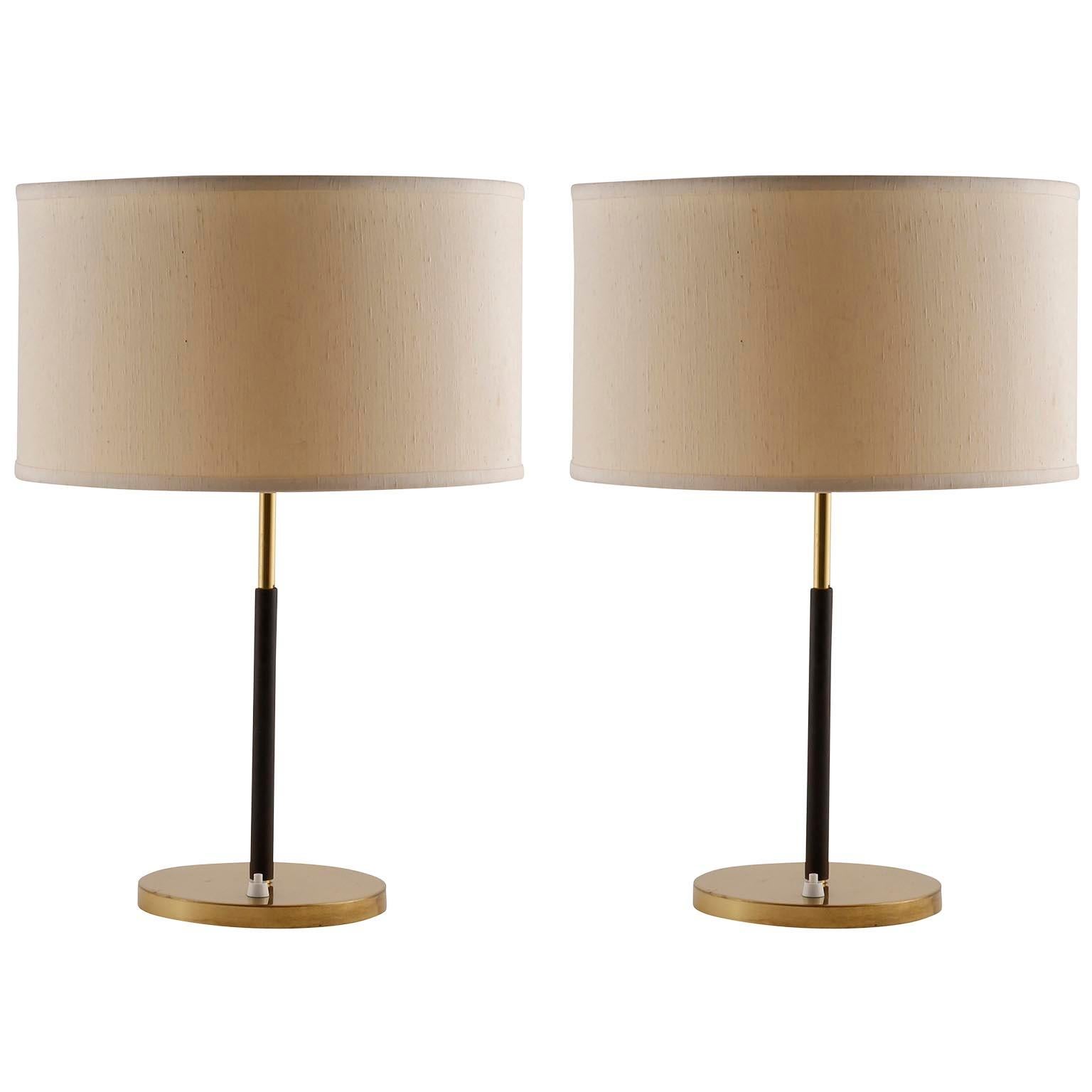 A pair of table lamps by J.T. Kalmar, manufactured in midcentury, circa 1960.
They are made of a brass covered base, a covered stand with dark brown leather, brass fittings, and a cream colored lampshade.
Each lamp takes two medium or standard screw
