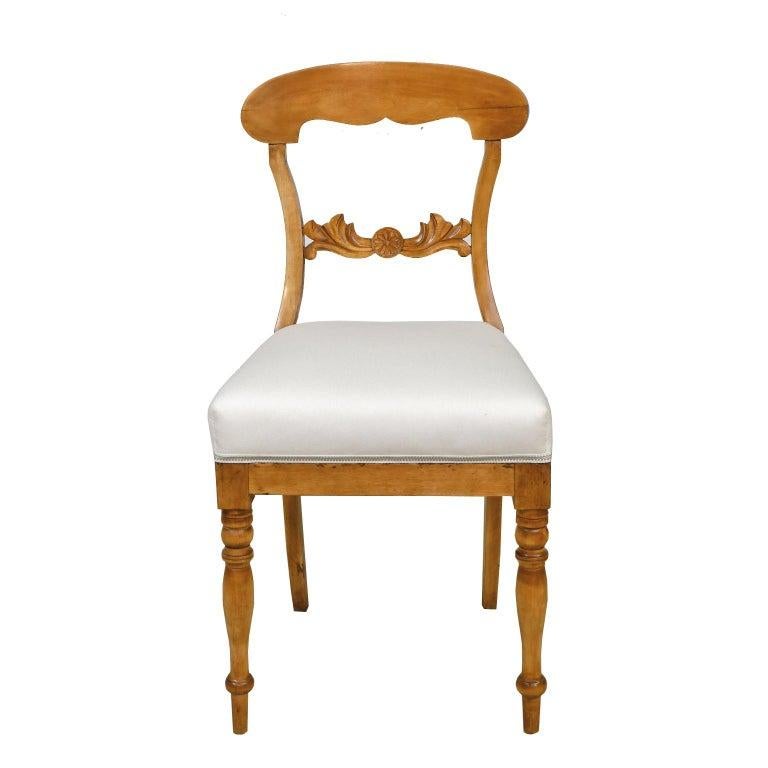 A lovely set of six Karl Johan dining chairs in a light, honey-colored birch wood with newly upholstered seat. Chairs have an arched crest rail, carved acanthus and rosette on back rail, turned front legs and saber rear legs, Sweden, circa 1825.